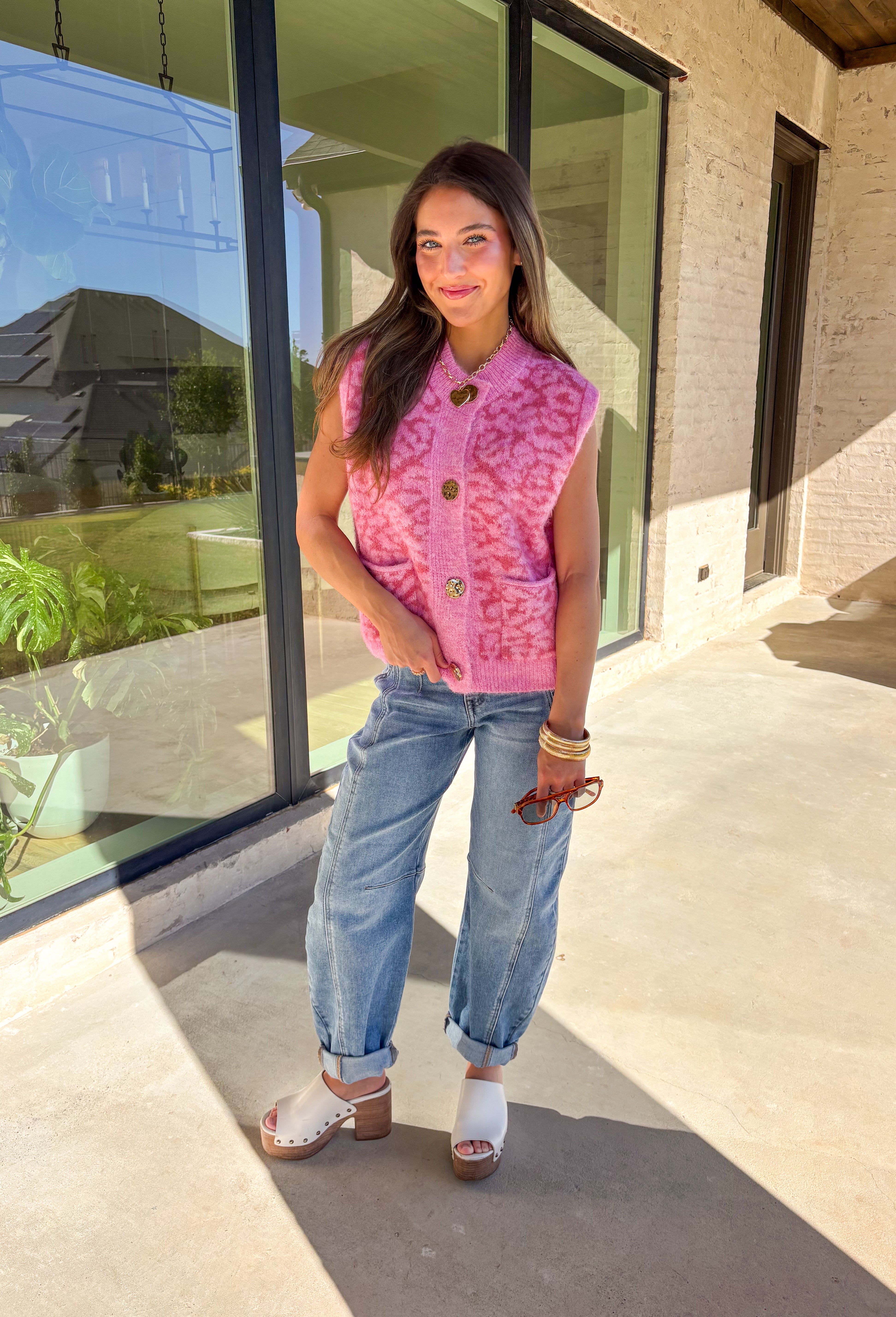 Add a touch of playful charm to your look with this shades-of-pink leopard print sleeveless sweater by &amp;Merci. Crafted in a soft, cozy knit, this piece features shiny gold buttons and two front pockets for a fun, vintage-inspired finish. The sleeveless design makes it perfect for layering or wearing solo during the warmer fall days.
