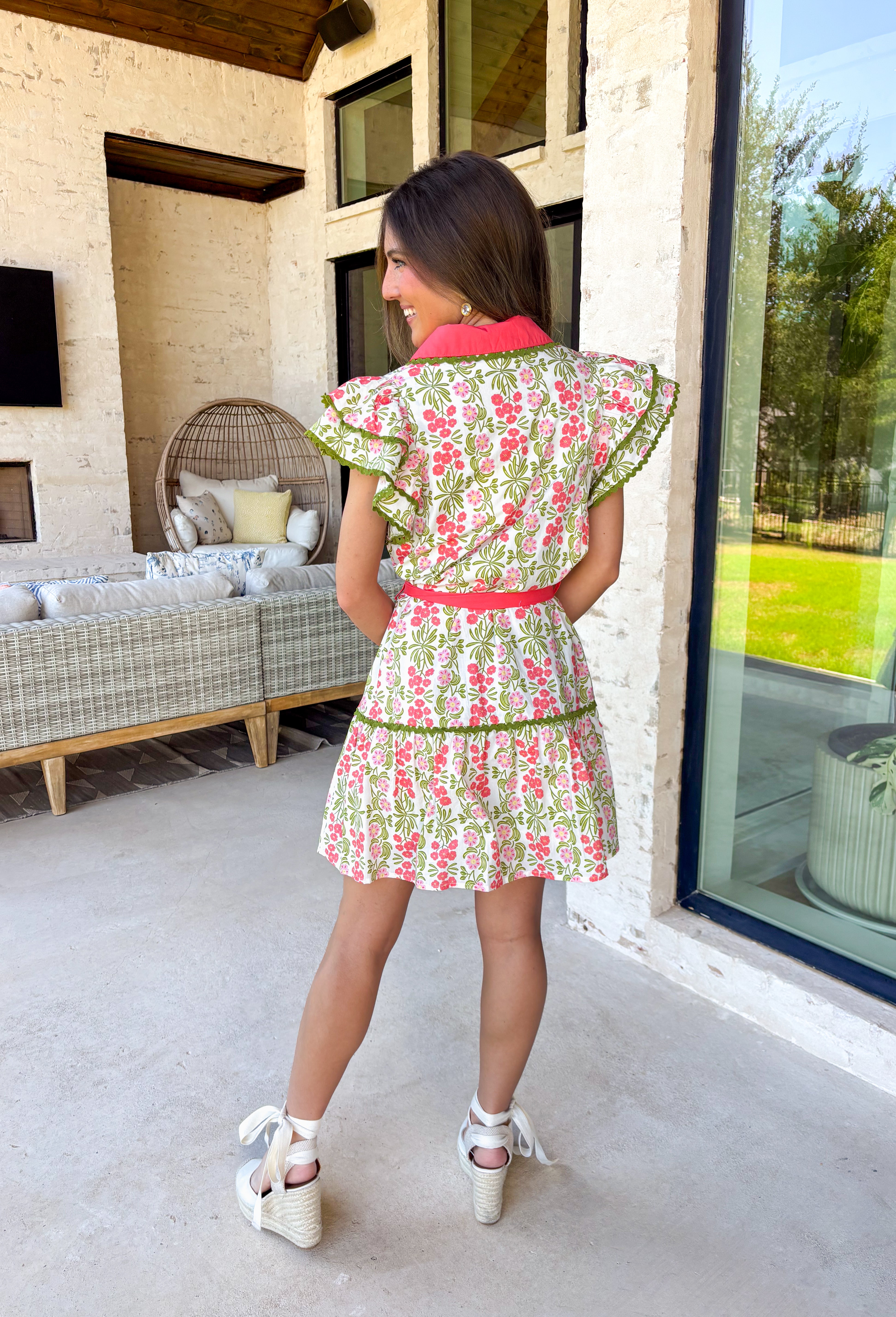 Fresh, feminine, and full of springtime charm, this off white midi dress is blooming with coral, green, and pink florals that instantly brighten your day. The collared neckline and button-down design give it a classic shirt dress feel, while the coral trim and green rick rack detailing along the front, skirt, and sleeves add the sweetest pop of playful contrast. The coral self-tie belt cinches the waist for a flattering silhouette that’s easy to adjust just how you like it.