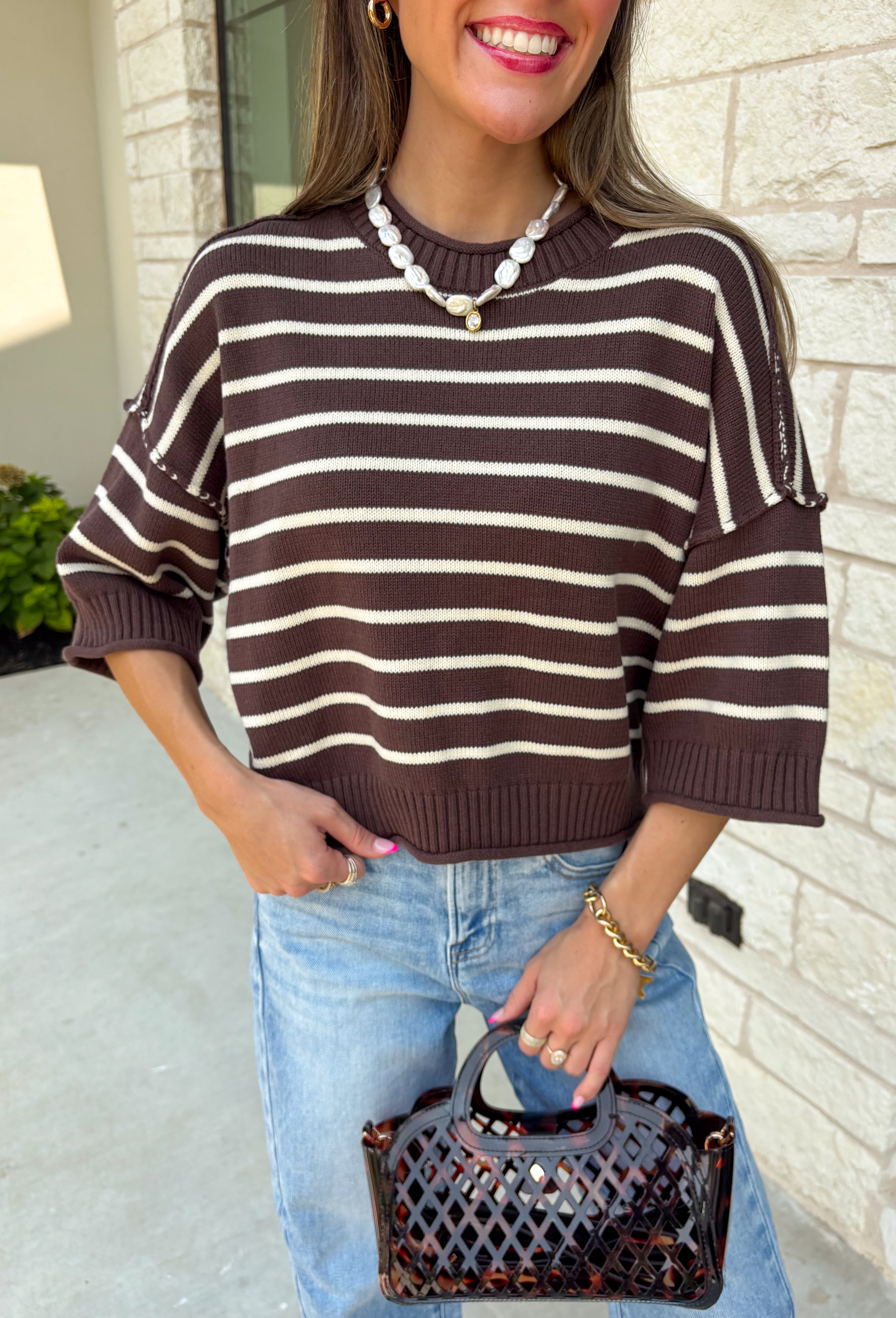 Wrap yourself in effortless fall style with this cozy striped sweater. Featuring a rich brown knit with timeless ivory stripes, this relaxed sweater is the perfect blend of classic and casual. Exposed seam details give it a laid-back feel, while the 3/4-length sleeves make it an easy piece to wear from the first cool mornings of the season through crisp autumn afternoons. Finished with a ribbed neckline, hem, and cuffs, it's a sweater you'll find yourself reaching for again and again.