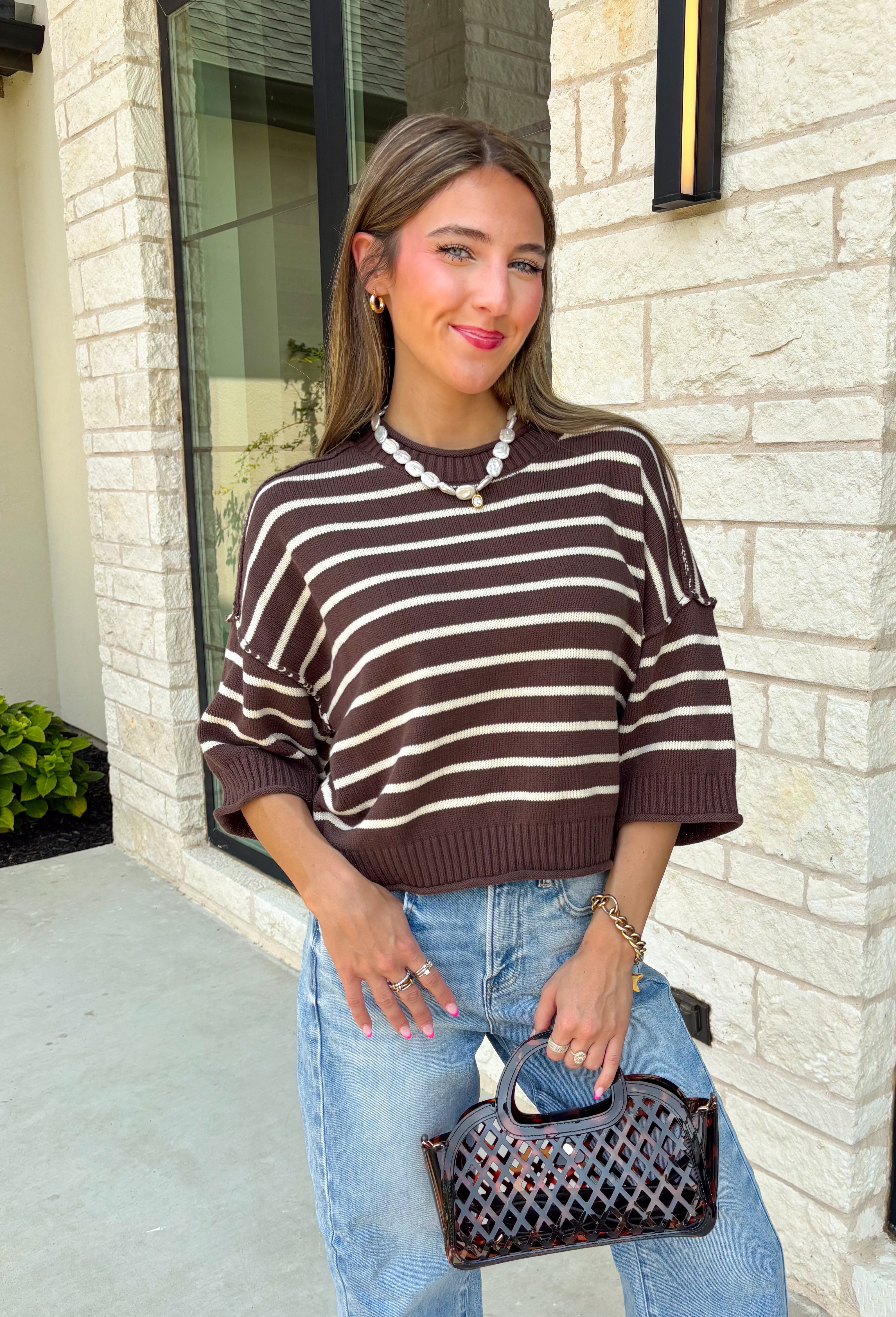 Wrap yourself in effortless fall style with this cozy striped sweater. Featuring a rich brown knit with timeless ivory stripes, this relaxed sweater is the perfect blend of classic and casual. Exposed seam details give it a laid-back feel, while the 3/4-length sleeves make it an easy piece to wear from the first cool mornings of the season through crisp autumn afternoons. Finished with a ribbed neckline, hem, and cuffs, it's a sweater you'll find yourself reaching for again and again.