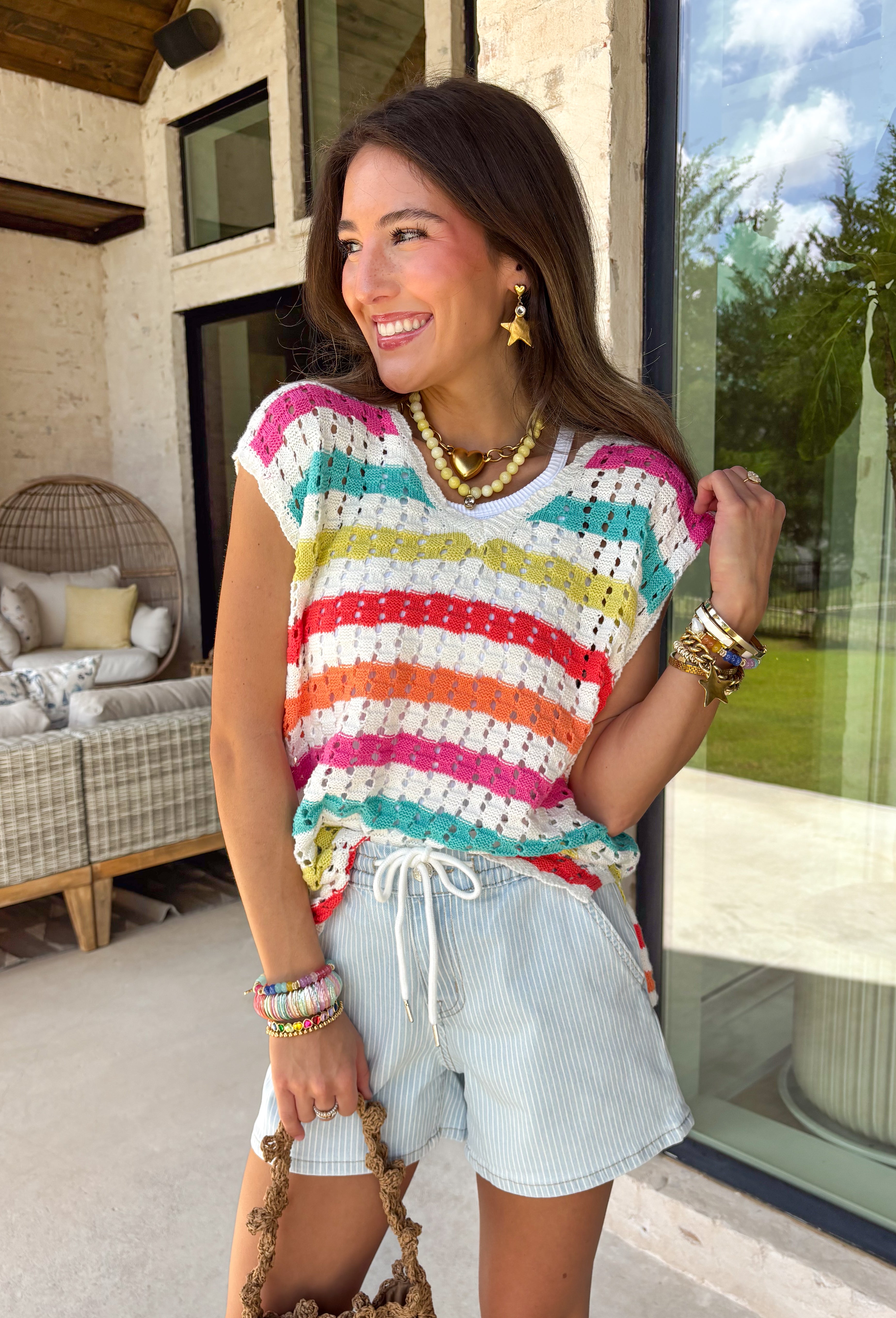 This open knit sweater tank is made for sunshine and warm days ahead. Designed in a soft off-white base with pops of orange, pink, blue, green, and red woven throughout, it brings just the right amount of playful color to your look. The breathable open knit design keeps it light and airy, making it perfect for layering over a bralette or tank when temperatures rise. Easy, effortless, and full of personality, this piece is a go-to for casual spring and summer styling.