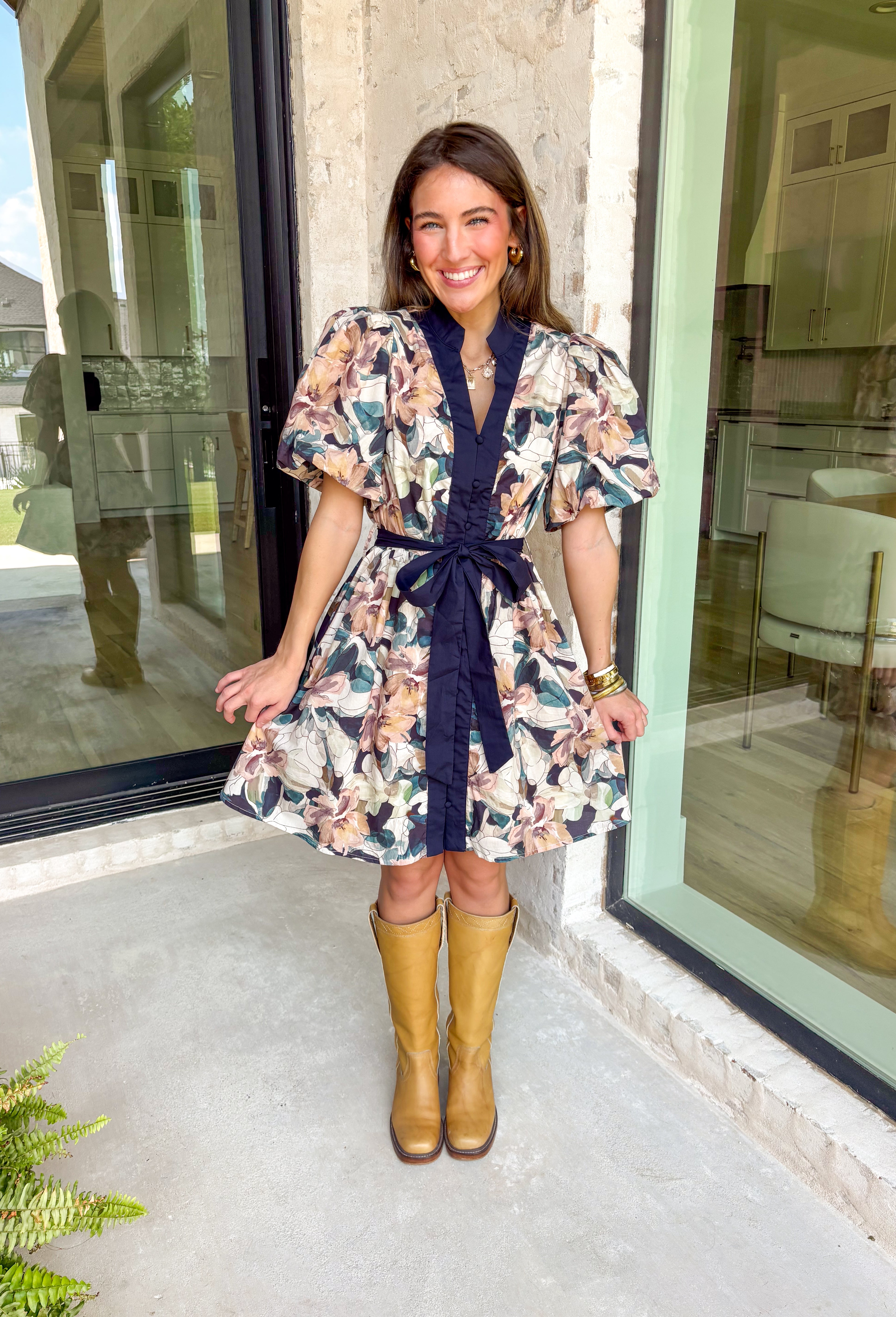 This navy floral dress is giving fall fabulous in the best way. With bold neutral blooms in cream, tan, teal, and brown, it’s the kind of that's perfect for any special occasion. The button-down design and matching self-tie waist keep things polished, while puff sleeves and navy trim down the front add a little extra charm.&nbsp;