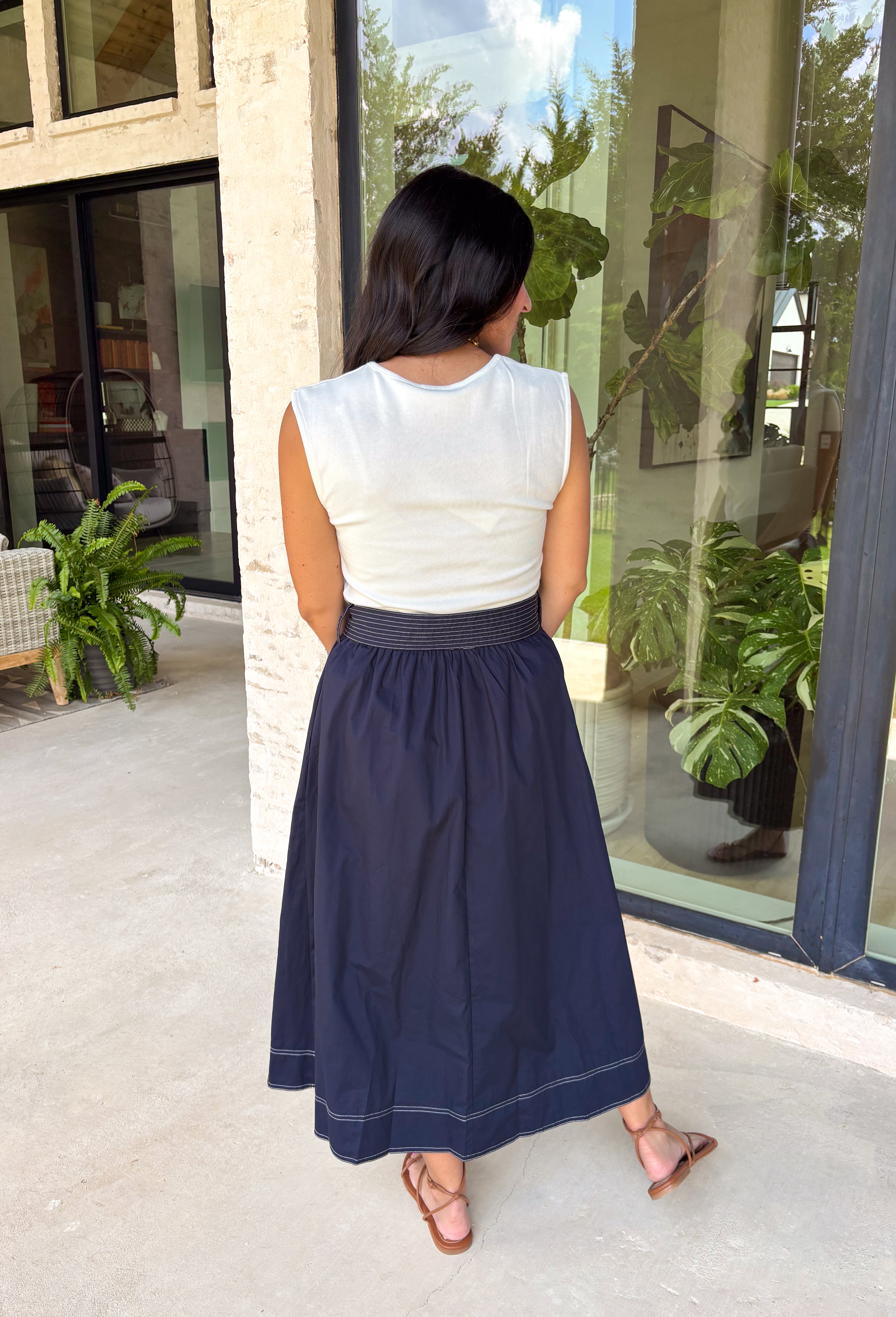 This sleeveless midi dress is the definition of effortless summer style! With its white top and navy skirt design, it gives you that perfectly layered look without any extra effort. The self-tie belt with white threading detail adds a flattering touch at the waist, while the matching detail along the hem pulls everything together beautifully. Lightweight, lined, and finished with side pockets, it’s as practical as it is polished. 
