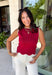 Classic with a touch of charm, this crimson sweater tank is made for the season ahead. The rich autumn hue is beautifully accented with crisp white trim and a delicate scalloped hem, creating a timeless look that's both polished and playful. Crafted from a soft sweater knit, it's perfect for layering under your favorite blazer, denim jacket, or cardigan as the temperatures begin to cool. 