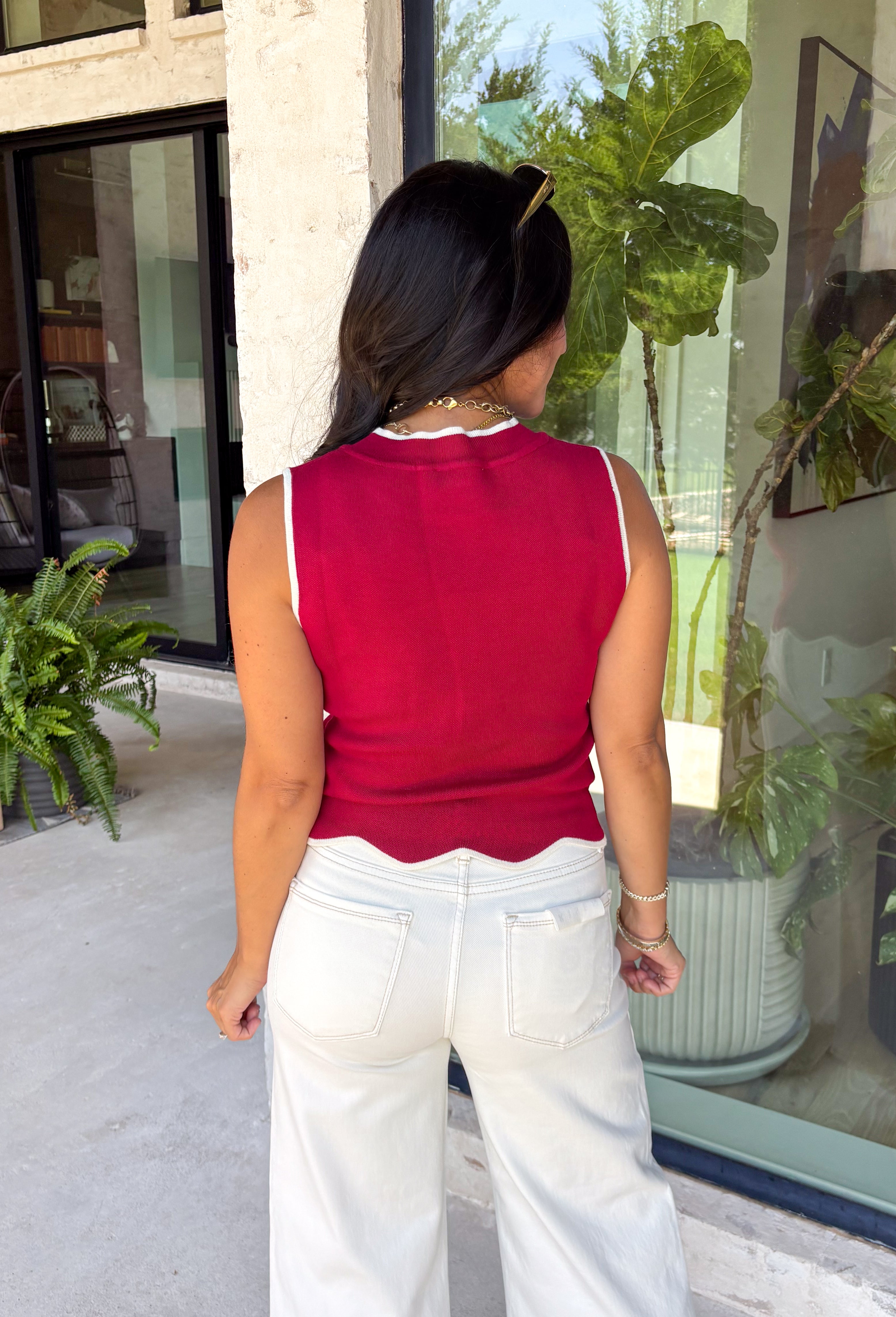 Classic with a touch of charm, this crimson sweater tank is made for the season ahead. The rich autumn hue is beautifully accented with crisp white trim and a delicate scalloped hem, creating a timeless look that's both polished and playful. Crafted from a soft sweater knit, it's perfect for layering under your favorite blazer, denim jacket, or cardigan as the temperatures begin to cool. 
