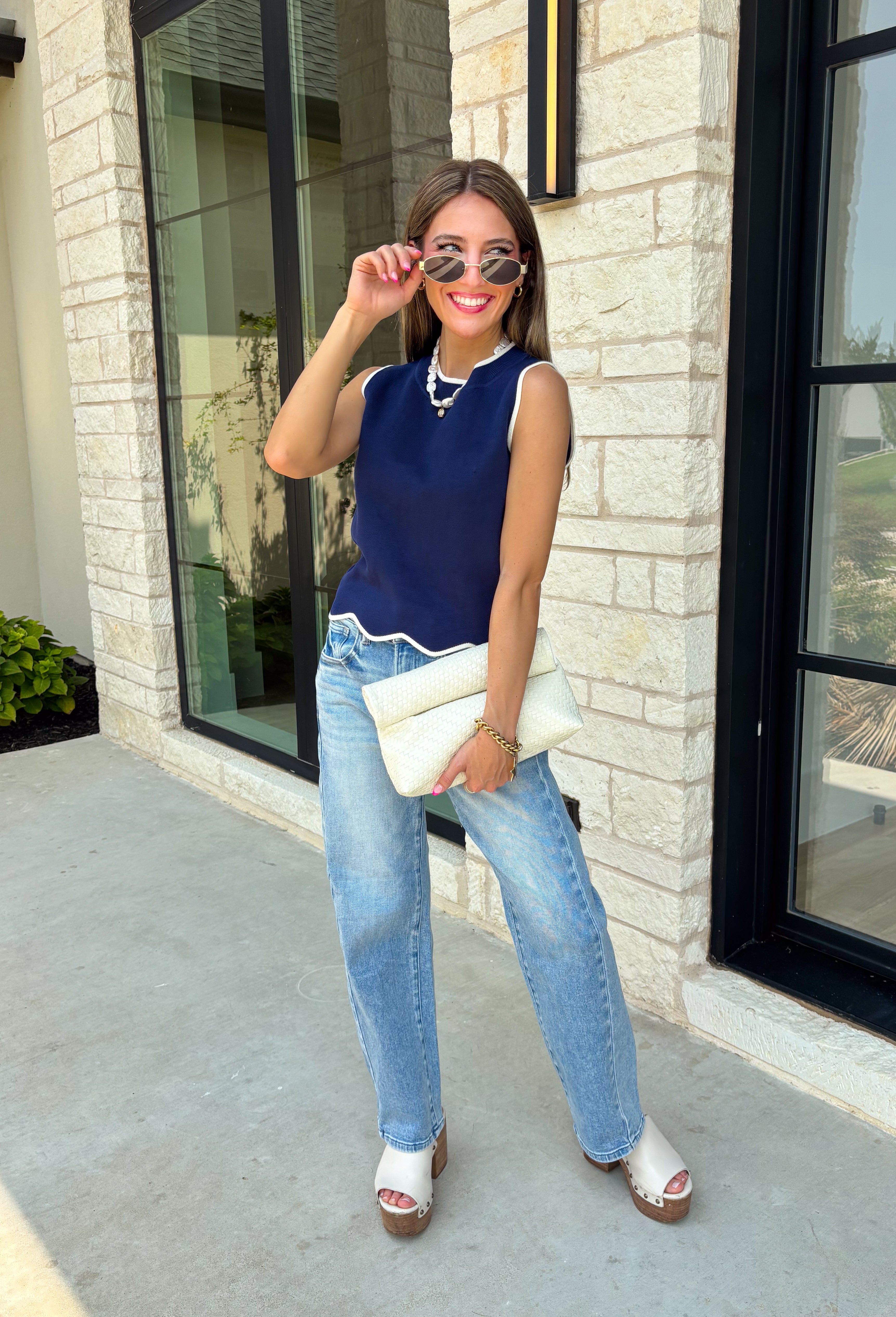 Classic with a touch of charm, this navy sweater tank is made for the season ahead. The rich autumn hue is beautifully accented with crisp white trim and a delicate scalloped hem, creating a timeless look that's both polished and playful. Crafted from a soft sweater knit, it's perfect for layering under your favorite blazer, denim jacket, or cardigan as the temperatures begin to cool. 