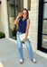 Classic with a touch of charm, this navy sweater tank is made for the season ahead. The rich autumn hue is beautifully accented with crisp white trim and a delicate scalloped hem, creating a timeless look that's both polished and playful. Crafted from a soft sweater knit, it's perfect for layering under your favorite blazer, denim jacket, or cardigan as the temperatures begin to cool. 