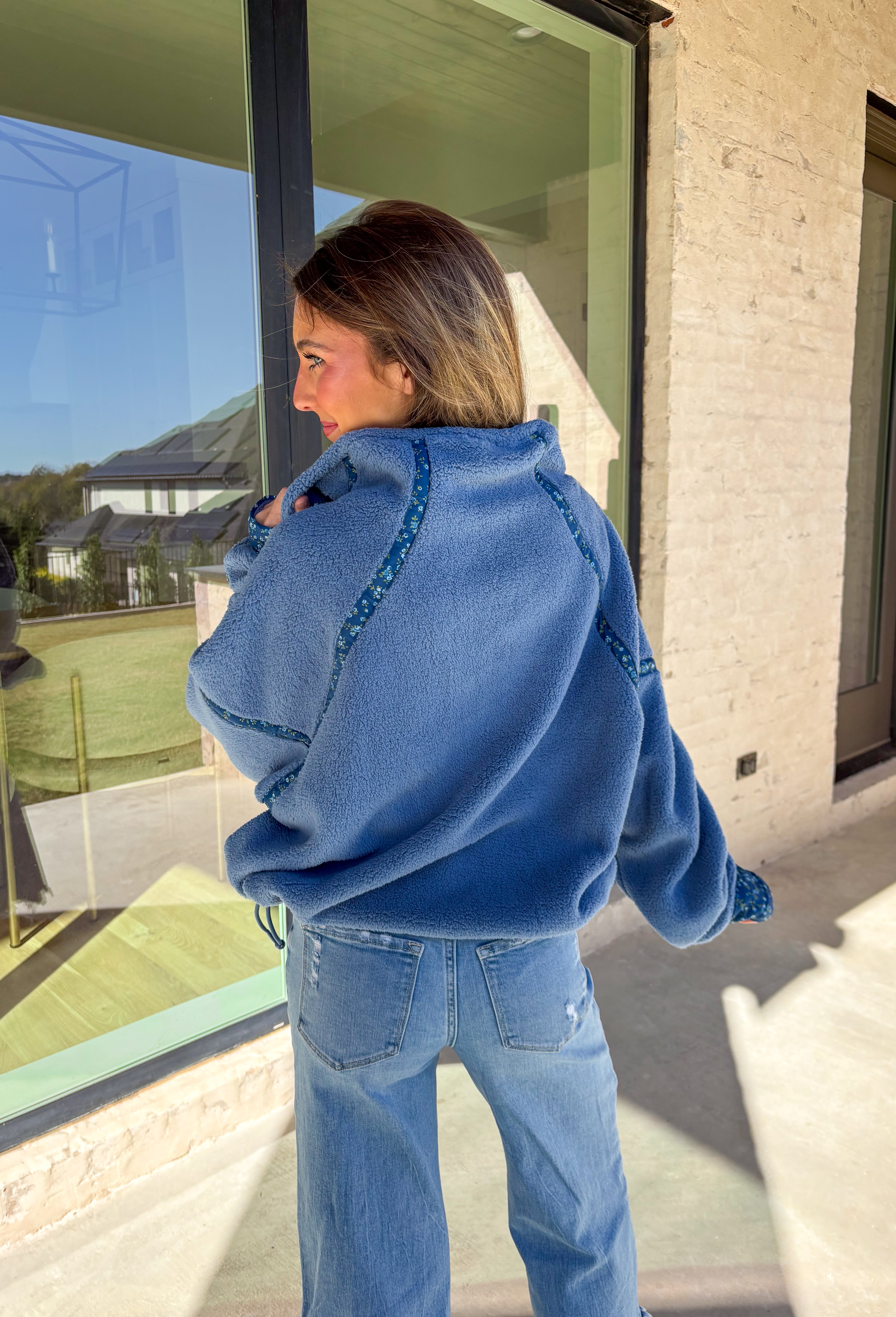 Bundle up in cozy comfort with this blue sherpa pullover by Peach Love. Featuring soft fleece fabric and a subtle floral print along the trim, this quarter-zip adds the perfect touch of femininity to a winter classic. The navy floral accents give it just the right amount of color, while the front pockets and plush texture make it a cold-weather favorite for lounging or layering.