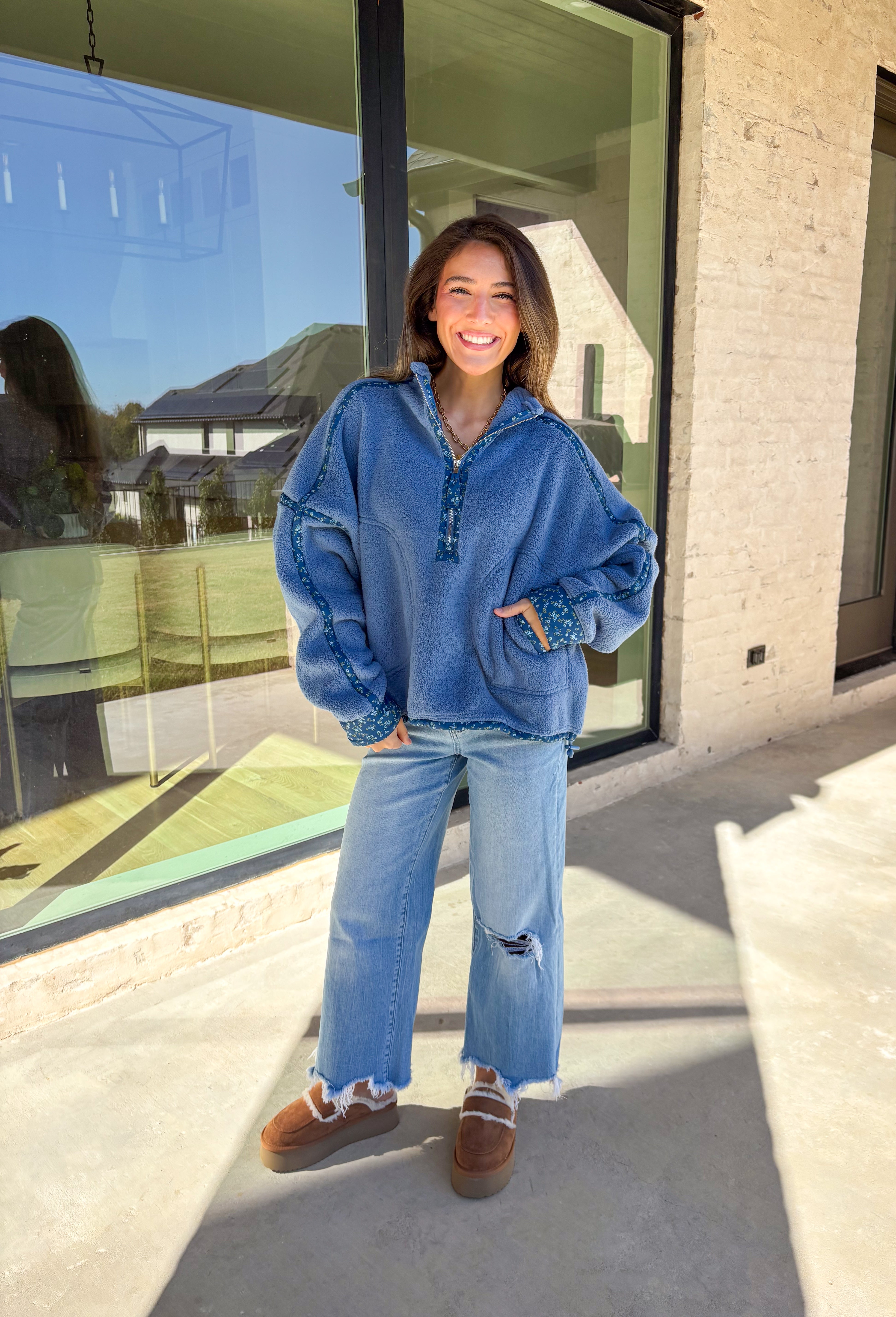 Bundle up in cozy comfort with this blue sherpa pullover by Peach Love. Featuring soft fleece fabric and a subtle floral print along the trim, this quarter-zip adds the perfect touch of femininity to a winter classic. The navy floral accents give it just the right amount of color, while the front pockets and plush texture make it a cold-weather favorite for lounging or layering.