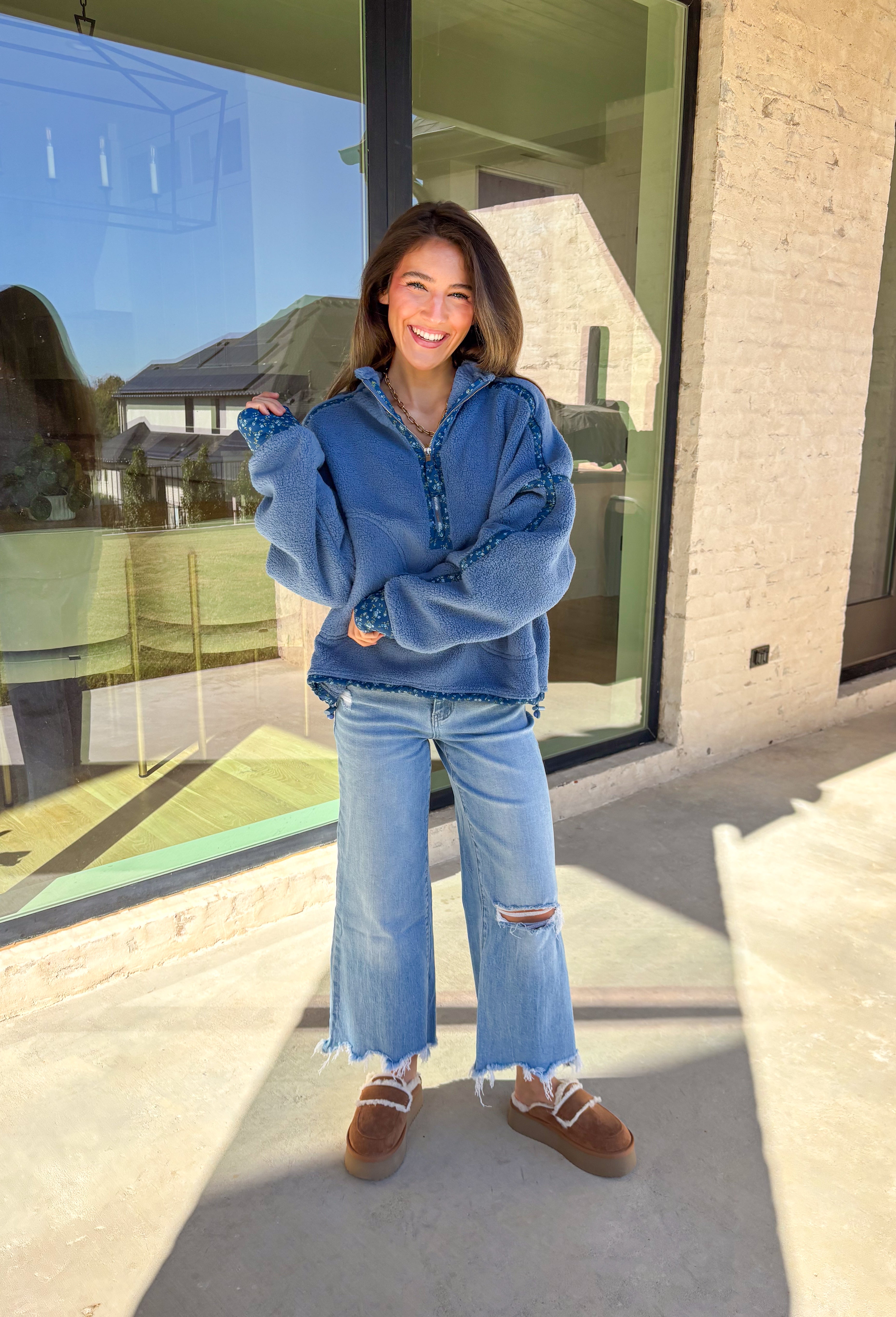 Bundle up in cozy comfort with this blue sherpa pullover by Peach Love. Featuring soft fleece fabric and a subtle floral print along the trim, this quarter-zip adds the perfect touch of femininity to a winter classic. The navy floral accents give it just the right amount of color, while the front pockets and plush texture make it a cold-weather favorite for lounging or layering.
