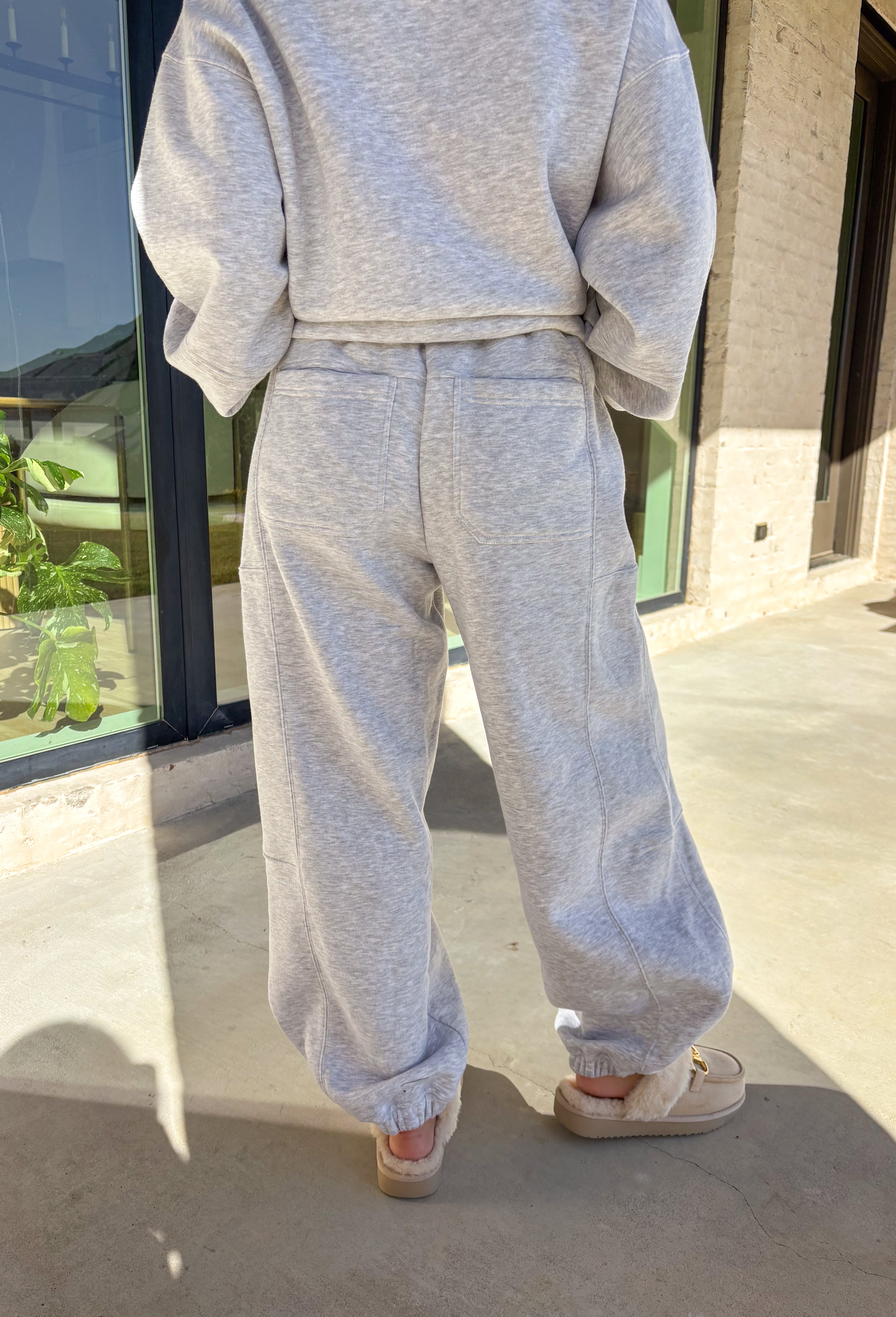 Stay cozy in style with these heather gray barrel joggers by Rae Mode. Lined in soft fleece and finished with a drawstring elastic waistband, these joggers offer the perfect blend of comfort and warmth for chilly winter days. Featuring side and back pockets for everyday convenience, their relaxed barrel silhouette makes them ideal for lounging or layering on the go. Pair them with the matching quarter-zip pullover for a complete cozy set or wear them solo for a laid-back, stylish look.