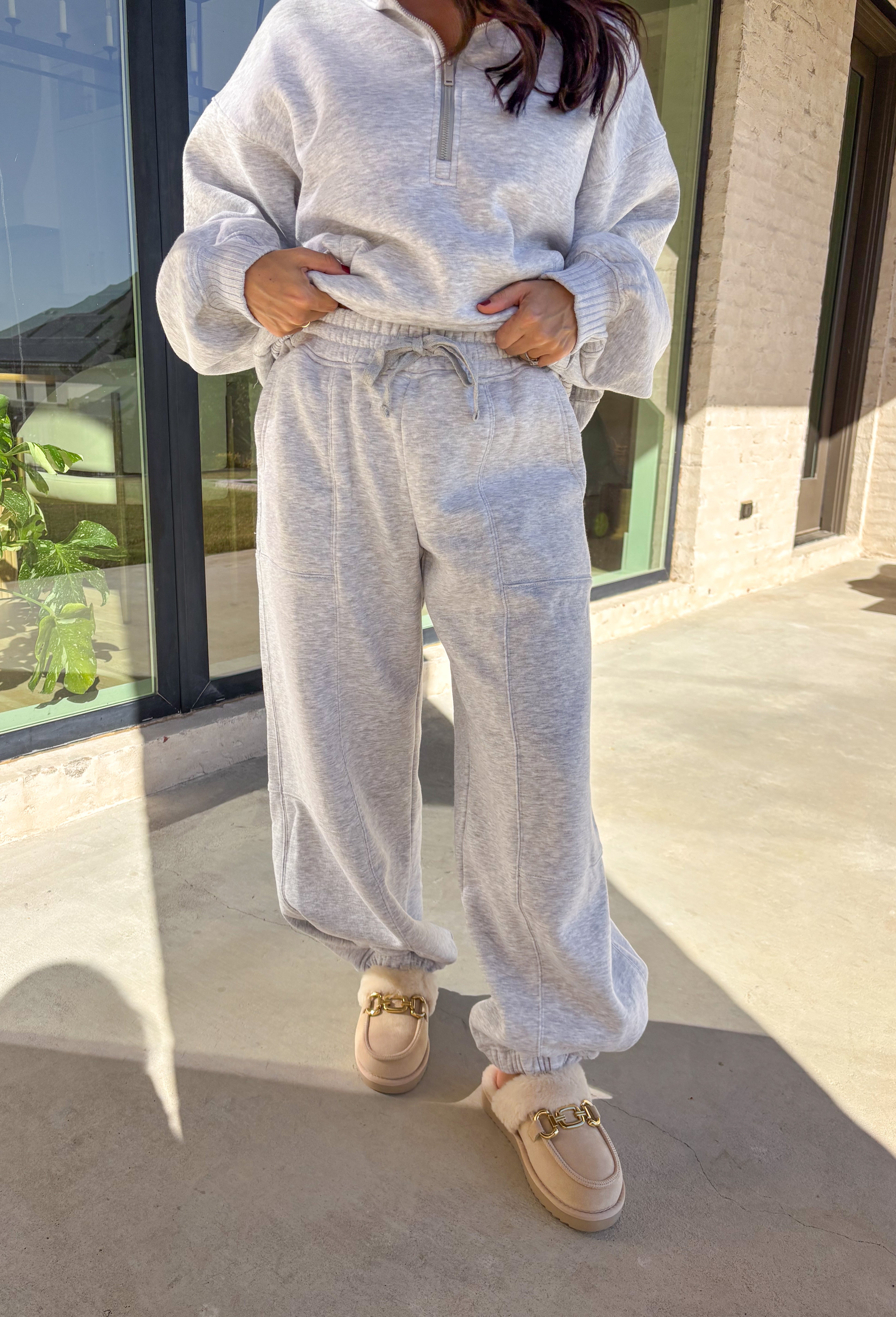 Stay cozy in style with these heather gray barrel joggers by Rae Mode. Lined in soft fleece and finished with a drawstring elastic waistband, these joggers offer the perfect blend of comfort and warmth for chilly winter days. Featuring side and back pockets for everyday convenience, their relaxed barrel silhouette makes them ideal for lounging or layering on the go. Pair them with the matching quarter-zip pullover for a complete cozy set or wear them solo for a laid-back, stylish look.