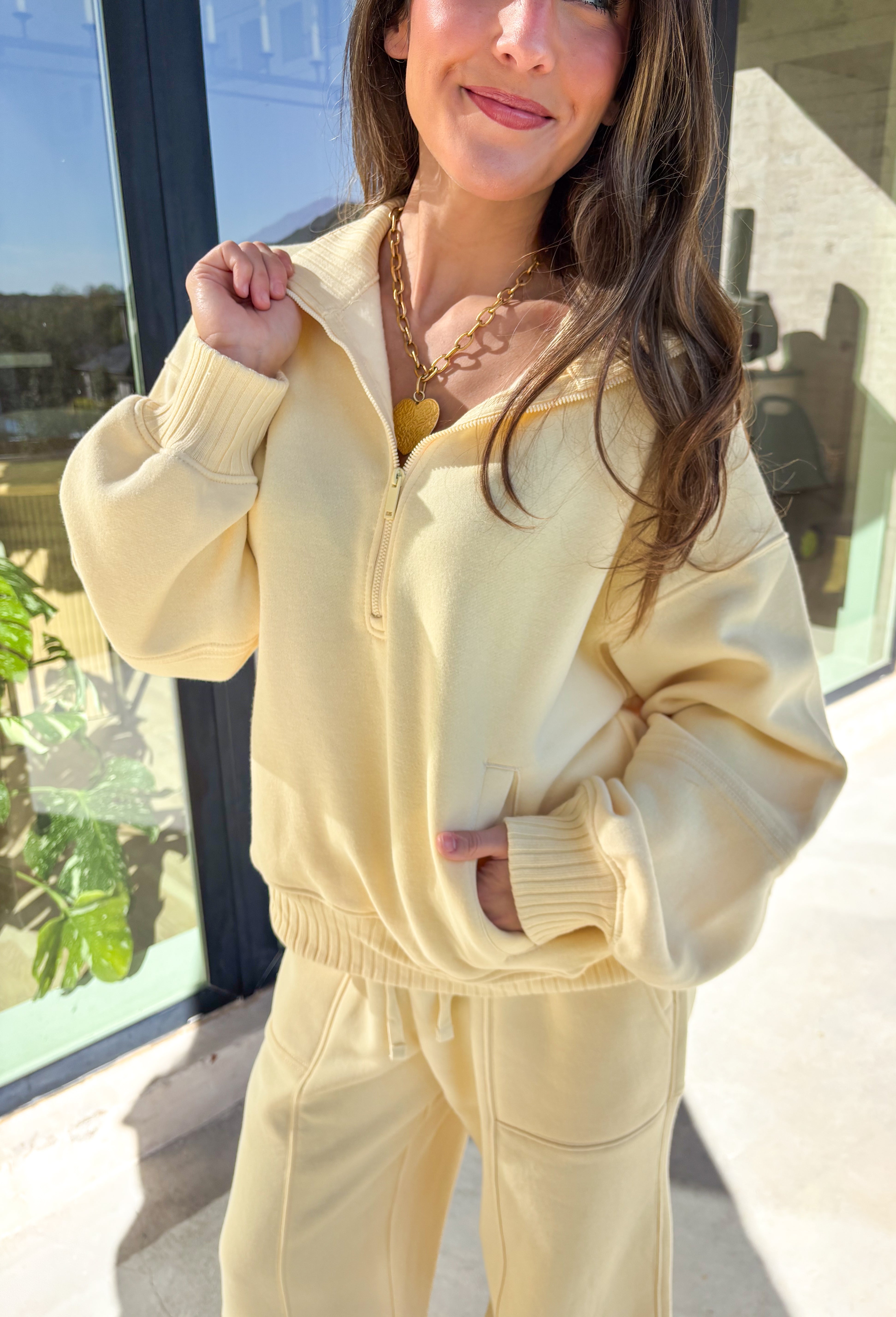 Cozy up this winter in the butter yellow fleece quarter zip pullover by Rae Mode. Designed with ribbed detailing along the collar, hem, and sleeve cuffs, this pullover combines a relaxed fit with an effortlessly polished look. The soft fleece interior and front pockets add extra warmth and comfort, making it the perfect throw-on for chilly days. Pair it with the matching joggers for the full set, or style it solo for an easy, laid-back outfit.