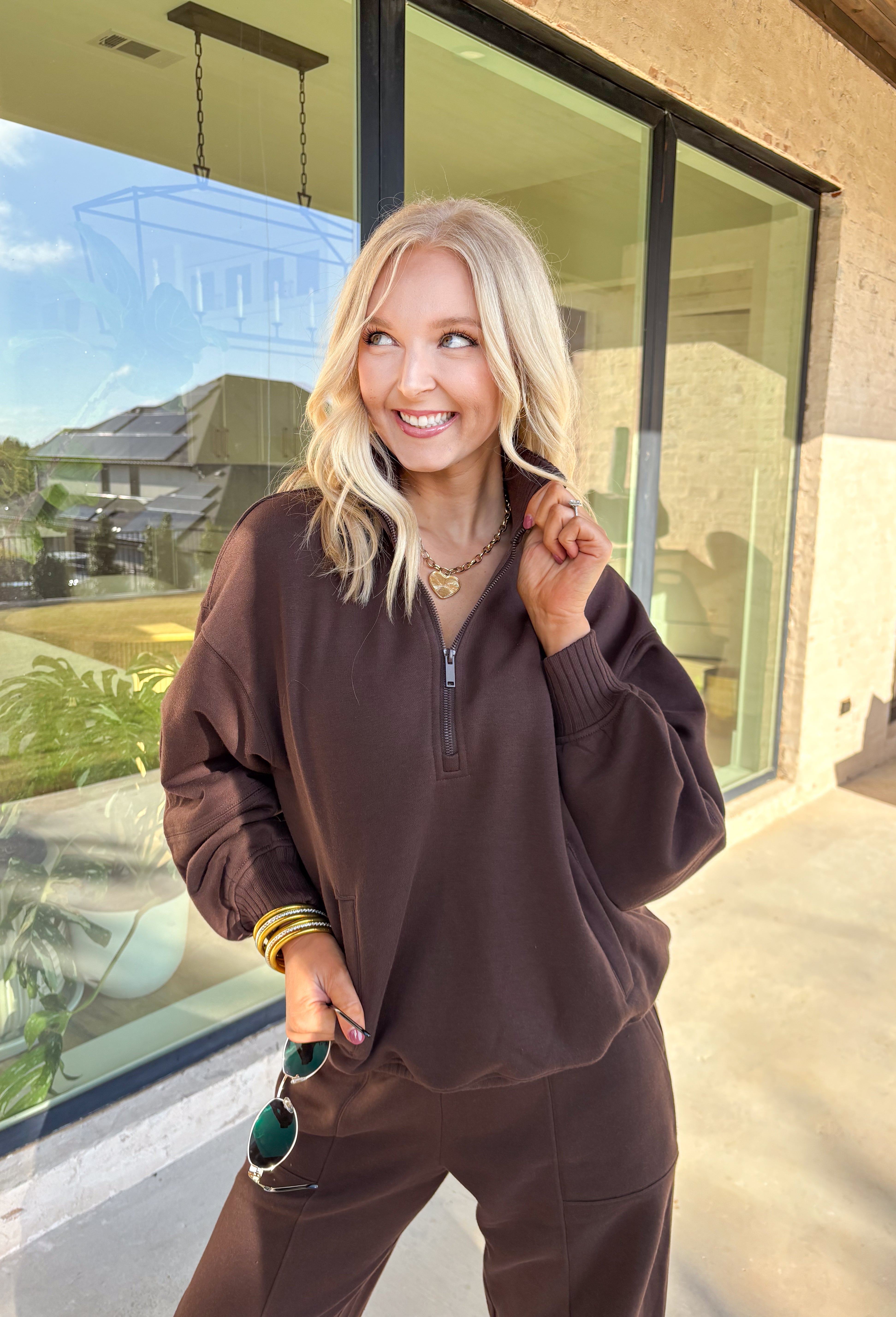 Cozy up this winter in the chocolate brown fleece quarter zip pullover by Rae Mode. Designed with ribbed detailing along the collar, hem, and sleeve cuffs, this pullover combines a relaxed fit with an effortlessly polished look. The soft fleece interior and front pockets add extra warmth and comfort, making it the perfect throw-on for chilly days. Pair it with the matching joggers for the full set, or style it solo for an easy, laid-back outfit.