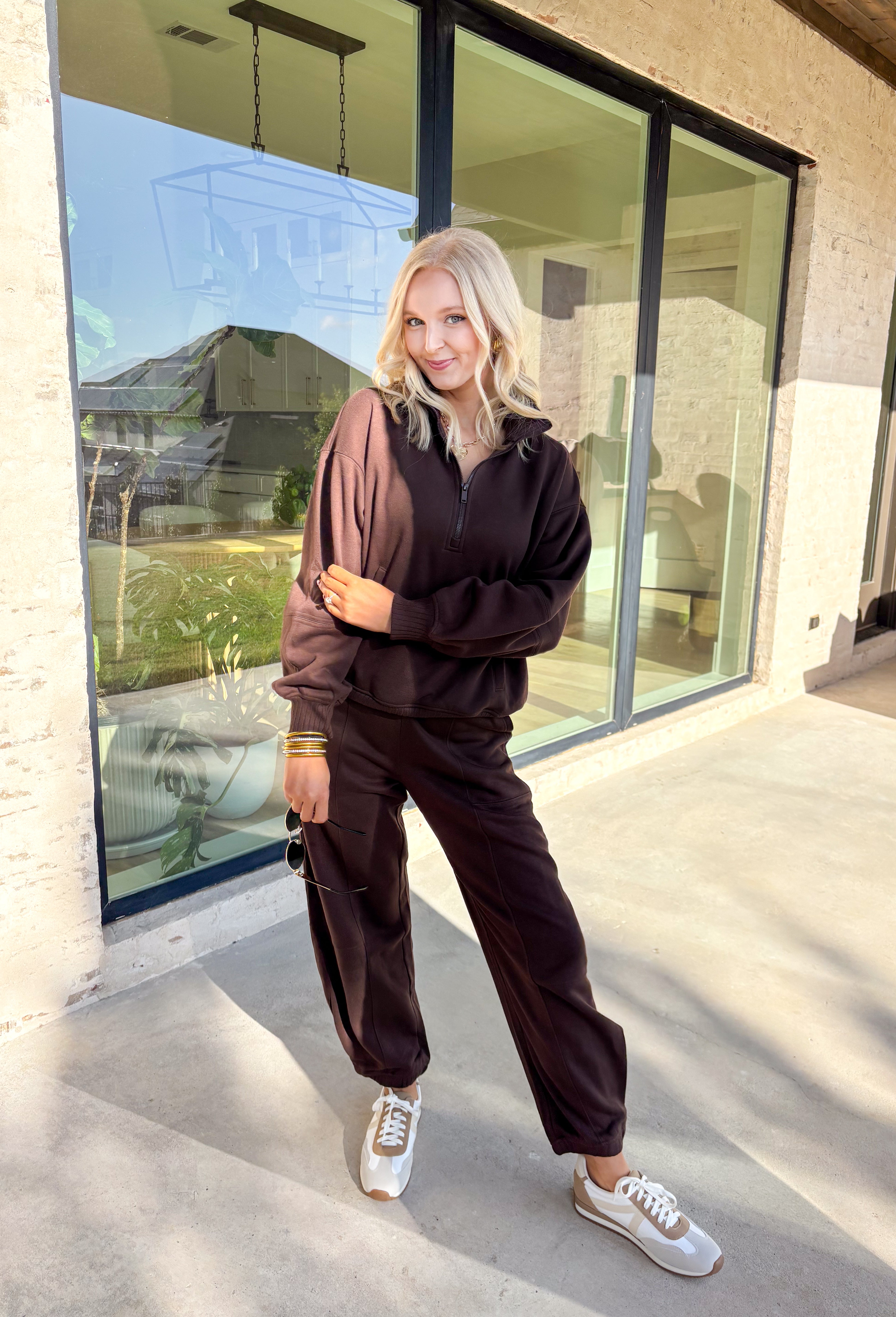 Cozy up this winter in the chocolate brown fleece quarter zip pullover by Rae Mode. Designed with ribbed detailing along the collar, hem, and sleeve cuffs, this pullover combines a relaxed fit with an effortlessly polished look. The soft fleece interior and front pockets add extra warmth and comfort, making it the perfect throw-on for chilly days. Pair it with the matching joggers for the full set, or style it solo for an easy, laid-back outfit.