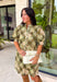 Classic plaid meets delicate florals in this charming dress from Entro. Designed with an olive plaid backdrop and a beautiful neutral floral print, this timeless piece is full of feminine details you'll love. The ruffled accent neck band collar adds an elegant touch, while the button-front closure and puff sleeves create an effortlessly polished silhouette. 