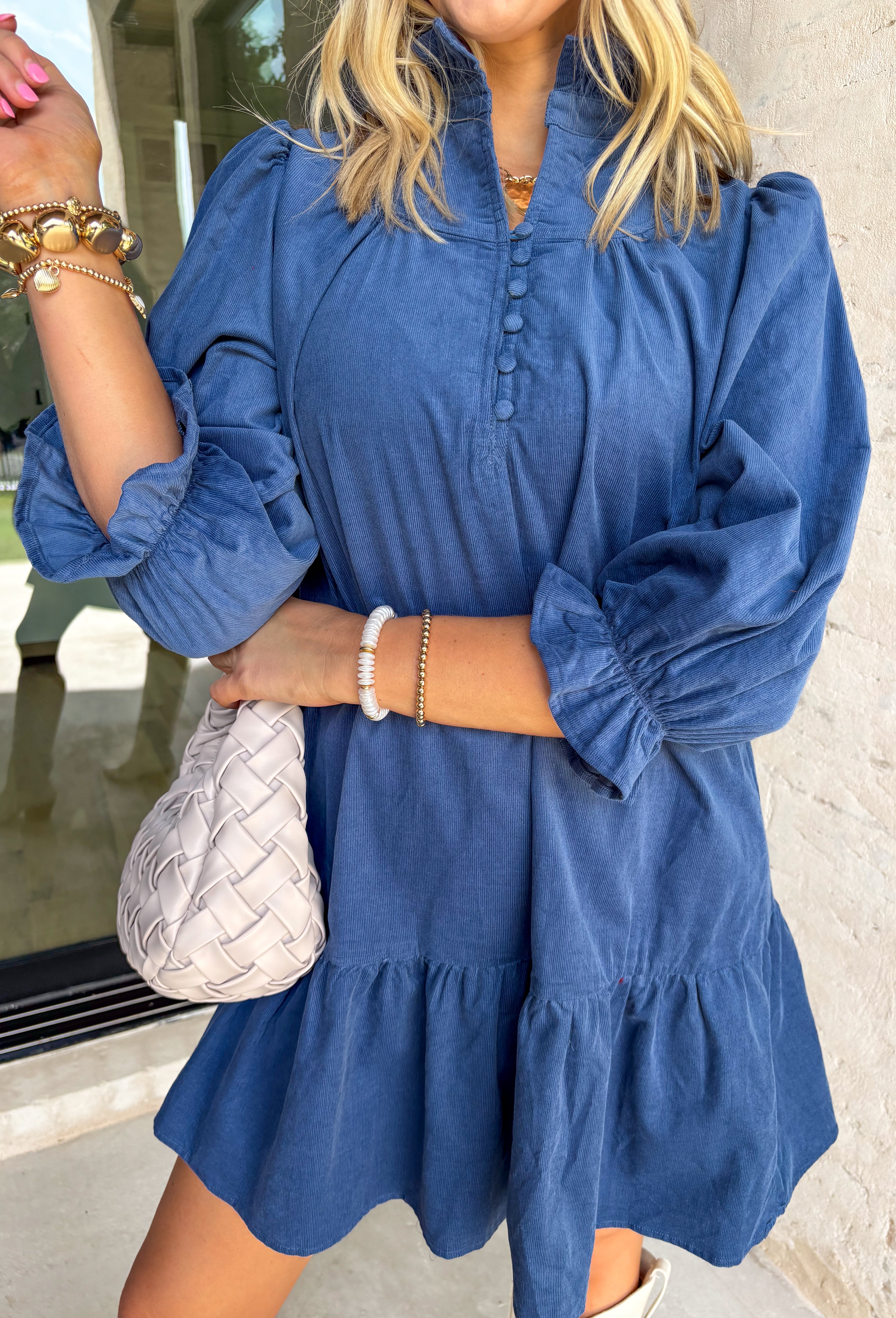 Corduroy gets a feminine refresh in this denim blue long sleeve dress. Designed with a tiered skirt for easy movement, it’s finished with front button details and a soft ruffle neckline that adds charm to the look. Smocked ruffle sleeves bring a cozy touch while keeping the fit comfortable, and the all-cotton construction makes it breathable enough for all-day wear. A perfect mix of texture and timeless design, this dress is a seasonal staple.