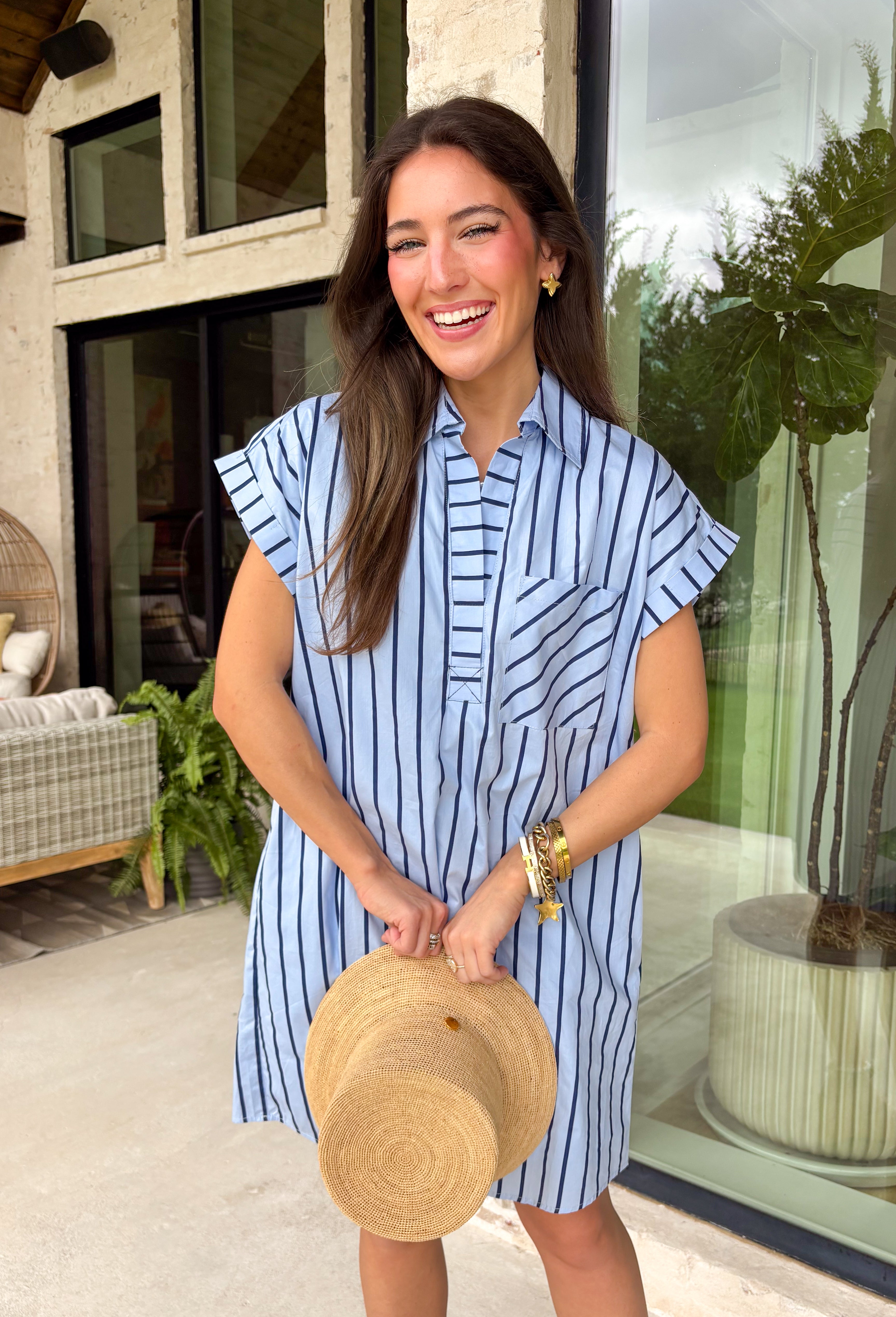 This light blue stripe dress is the kind of easy, polished piece you’ll reach for all summer long! The navy stripe print keeps it classic, while the collared v-neckline adds a slightly elevated touch that still feels effortless. With cuffed sleeves and a front pocket, it has that relaxed, everyday feel—plus side pockets (always a win). Made from breathable cotton and fully lined, it’s comfortable enough for all-day wear. From errands to lunch plans, this dress makes getting ready simple. 