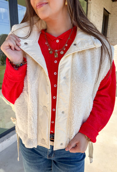 Layer on the warmth with this off white sherpa vest, the perfect cozy piece for winter. Designed with a button-down front and ivory trim, it’s accented with side pockets for practicality and tie details on the sides for an adjustable fit. The plush sherpa texture makes it a must-have layering piece, whether you’re throwing it over a chunky sweater or styling it with a casual flannel. This vest blends comfort and style for the season’s coldest days.