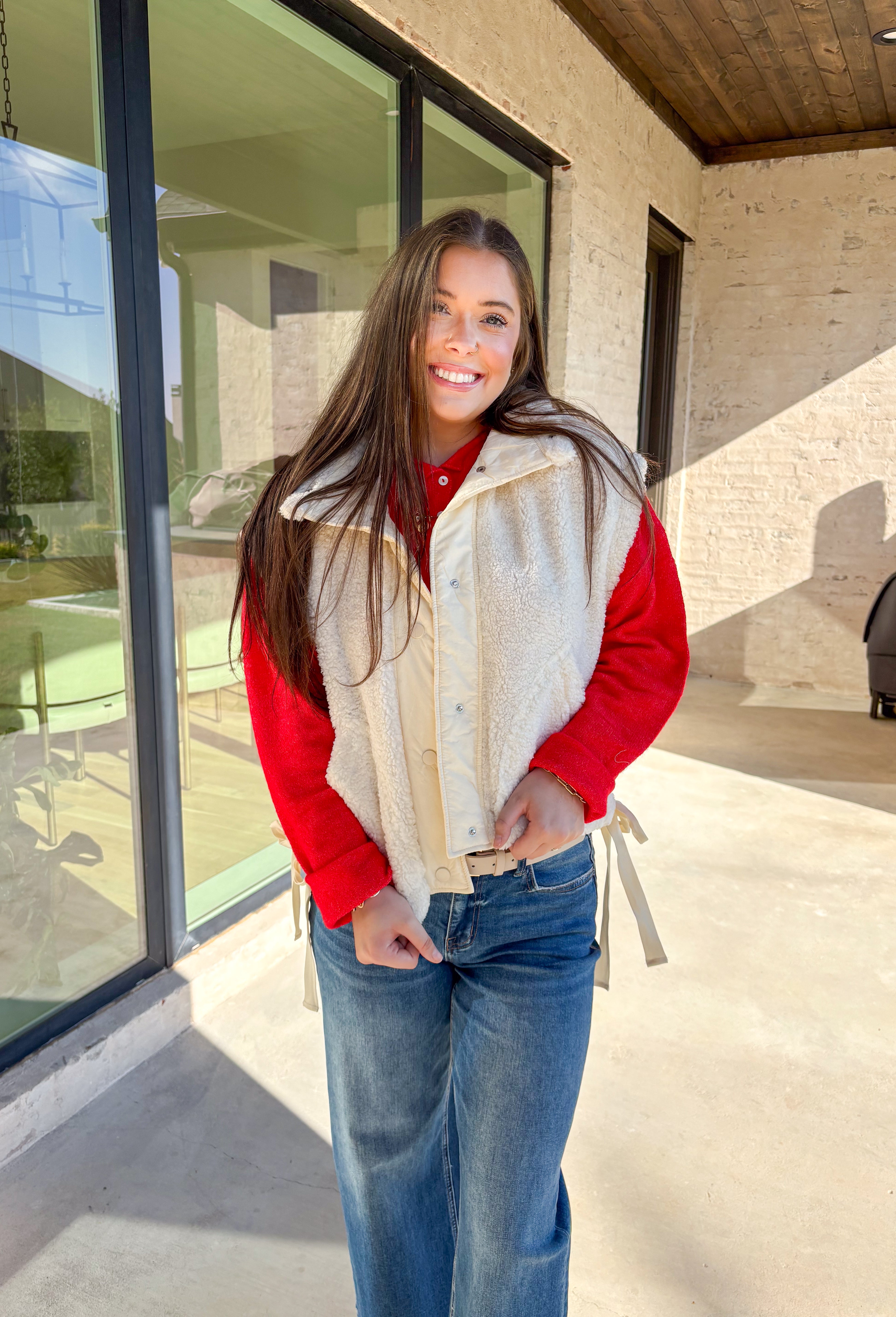 Layer on the warmth with this off white sherpa vest, the perfect cozy piece for winter. Designed with a button-down front and ivory trim, it’s accented with side pockets for practicality and tie details on the sides for an adjustable fit. The plush sherpa texture makes it a must-have layering piece, whether you’re throwing it over a chunky sweater or styling it with a casual flannel. This vest blends comfort and style for the season’s coldest days.