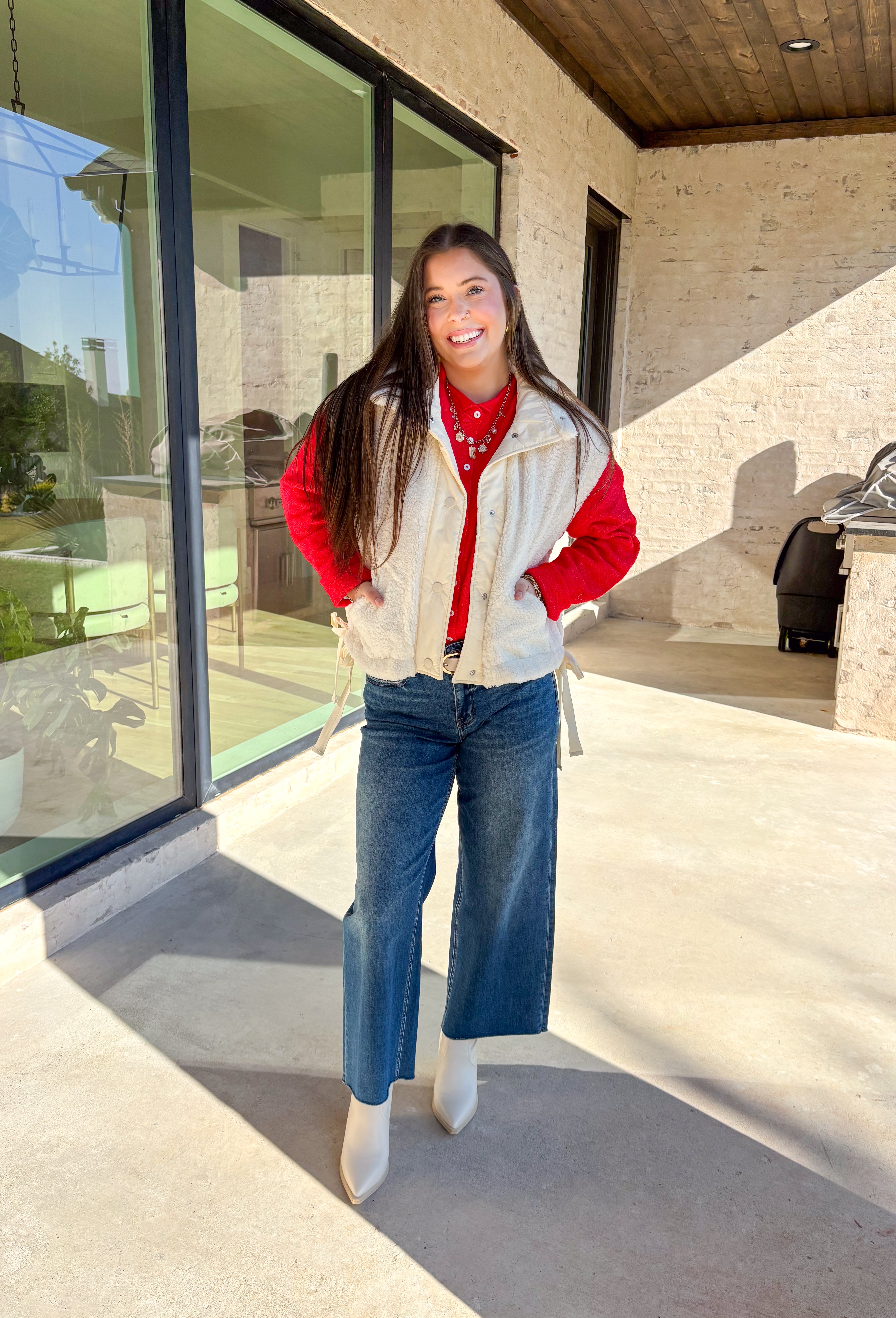 Layer on the warmth with this off white sherpa vest, the perfect cozy piece for winter. Designed with a button-down front and ivory trim, it’s accented with side pockets for practicality and tie details on the sides for an adjustable fit. The plush sherpa texture makes it a must-have layering piece, whether you’re throwing it over a chunky sweater or styling it with a casual flannel. This vest blends comfort and style for the season’s coldest days.