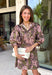 Bring effortless charm to your fall wardrobe with this beautifully detailed dress from Entro. Designed in a rich olive hue with a delicate floral print in shades of light pink and black, this timeless dress is perfect for everything from brunch dates to weekend outings. The stand neckline and partial button-front closure create a polished silhouette, while the ¾ puff sleeves are finished with sweet tie cuffs for an extra feminine touch. 