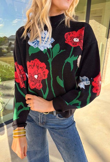 Add a touch of bold beauty to your winter wardrobe with this black mock neck sweater by Entro. Featuring a large-scale floral print in red, blue, green, tan, and off-white, this cozy knit makes a striking statement while keeping you warm. The mock neckline and soft stretch fabric make it perfect for chilly days—easy to dress up or wear casually through the season.