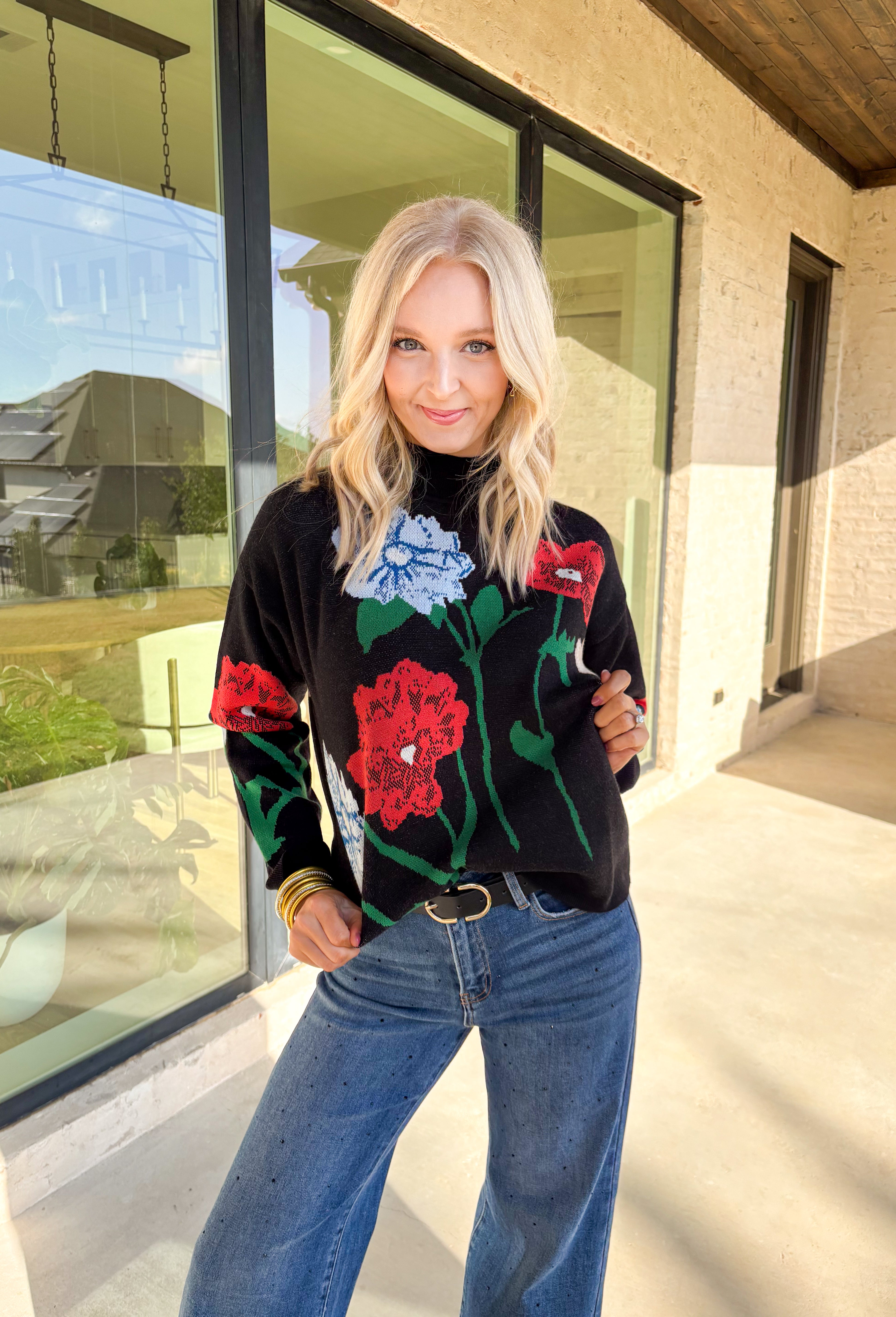 Add a touch of bold beauty to your winter wardrobe with this black mock neck sweater by Entro. Featuring a large-scale floral print in red, blue, green, tan, and off-white, this cozy knit makes a striking statement while keeping you warm. The mock neckline and soft stretch fabric make it perfect for chilly days—easy to dress up or wear casually through the season.