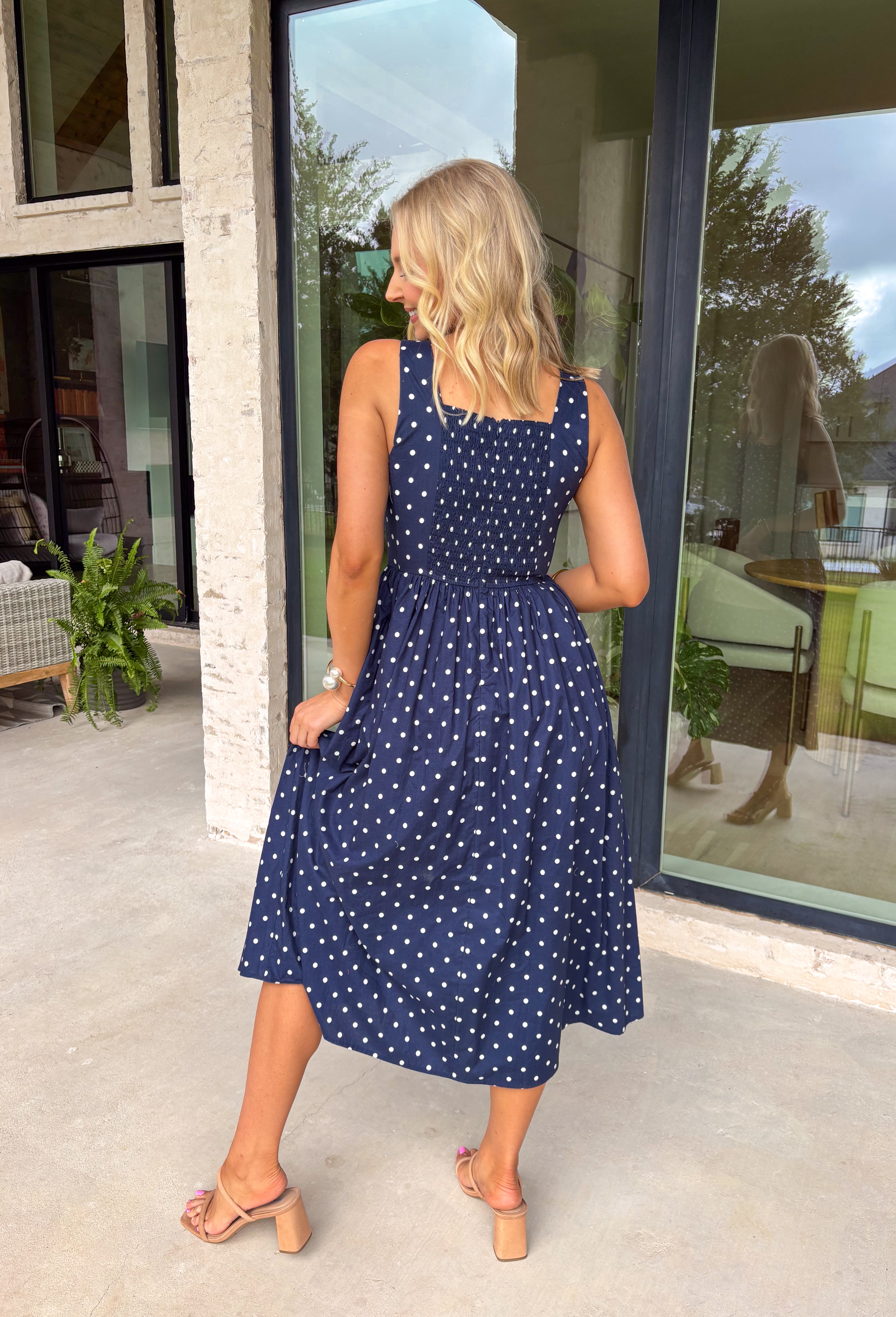 Timeless, feminine, and effortlessly polished! This navy midi dress features a classic white polka dot print that never goes out of style. The square neckline creates a flattering, structured silhouette, while the sleeveless design keeps it light and perfect for warm days. Smocking along the back bodice provides comfortable stretch and a beautiful fit, while the back zipper closure keeps the look clean and tailored. Finished with side pockets and breathable cotton fabric.
