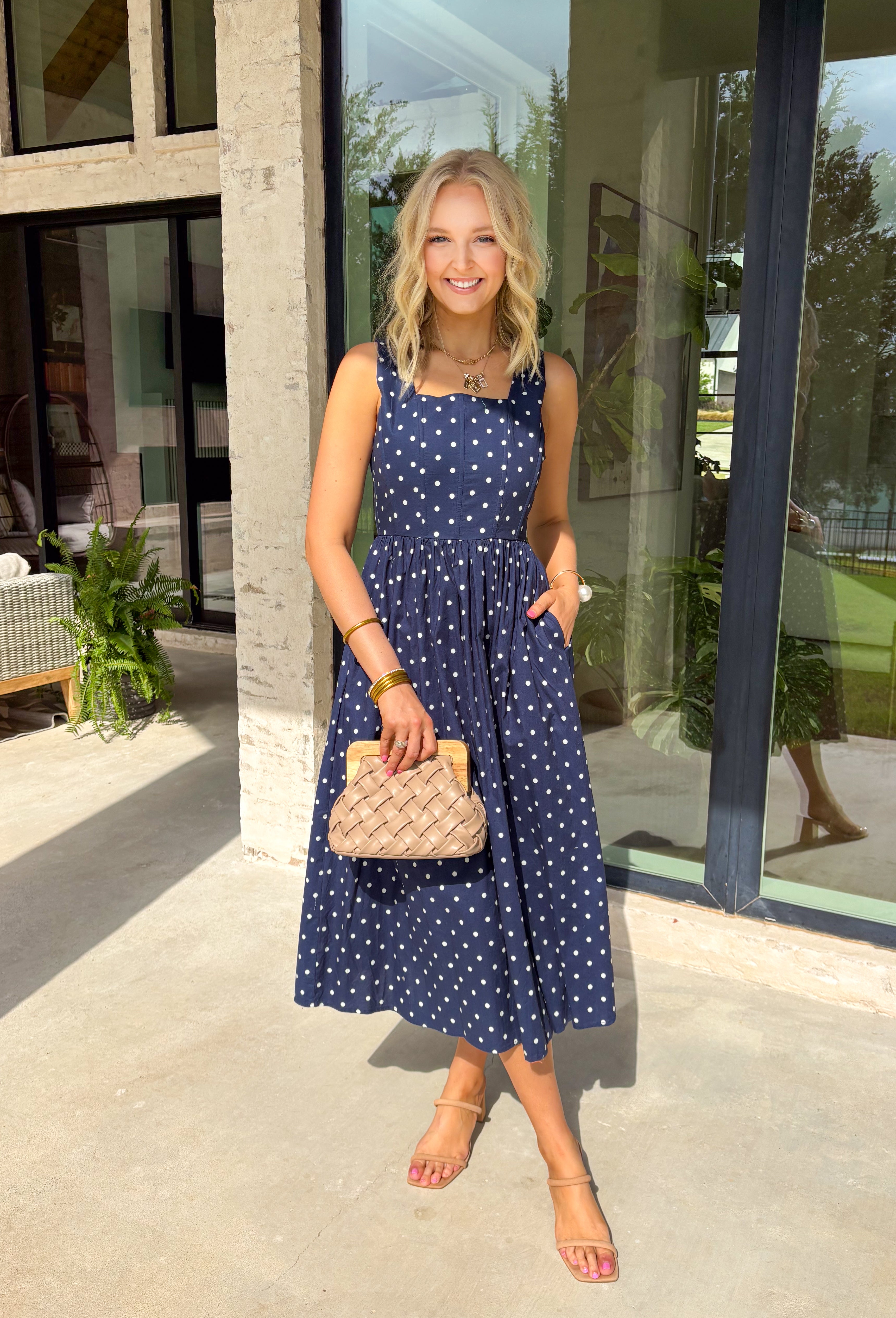 Timeless, feminine, and effortlessly polished! This navy midi dress features a classic white polka dot print that never goes out of style. The square neckline creates a flattering, structured silhouette, while the sleeveless design keeps it light and perfect for warm days. Smocking along the back bodice provides comfortable stretch and a beautiful fit, while the back zipper closure keeps the look clean and tailored. Finished with side pockets and breathable cotton fabric.