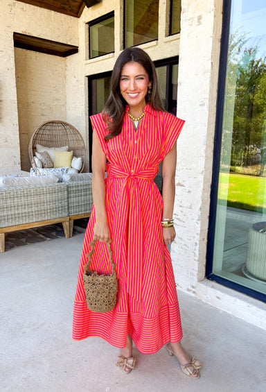 Bold, bright, and made for sunshine—this striped cap sleeve midi dress by Entro is a total spring-and-summer mood. With its vibrant orange and hot pink stripe combo, it’s the kind of dress that instantly makes you feel happy the second you put it on. The v-neckline is finished with a cute self-tie detail at the front, giving it a playful, flattering touch that feels extra special without being too much. 