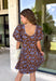 Bring timeless elegance to your fall wardrobe with this beautifully detailed dress from Entro. Designed with a rich brown backdrop and a stunning blue floral print, this feminine dress is full of eye-catching seasonal charm. The flattering square neckline is accented with beautiful blue contrast trim, while the pleated waist creates a flattering, defined silhouette. 