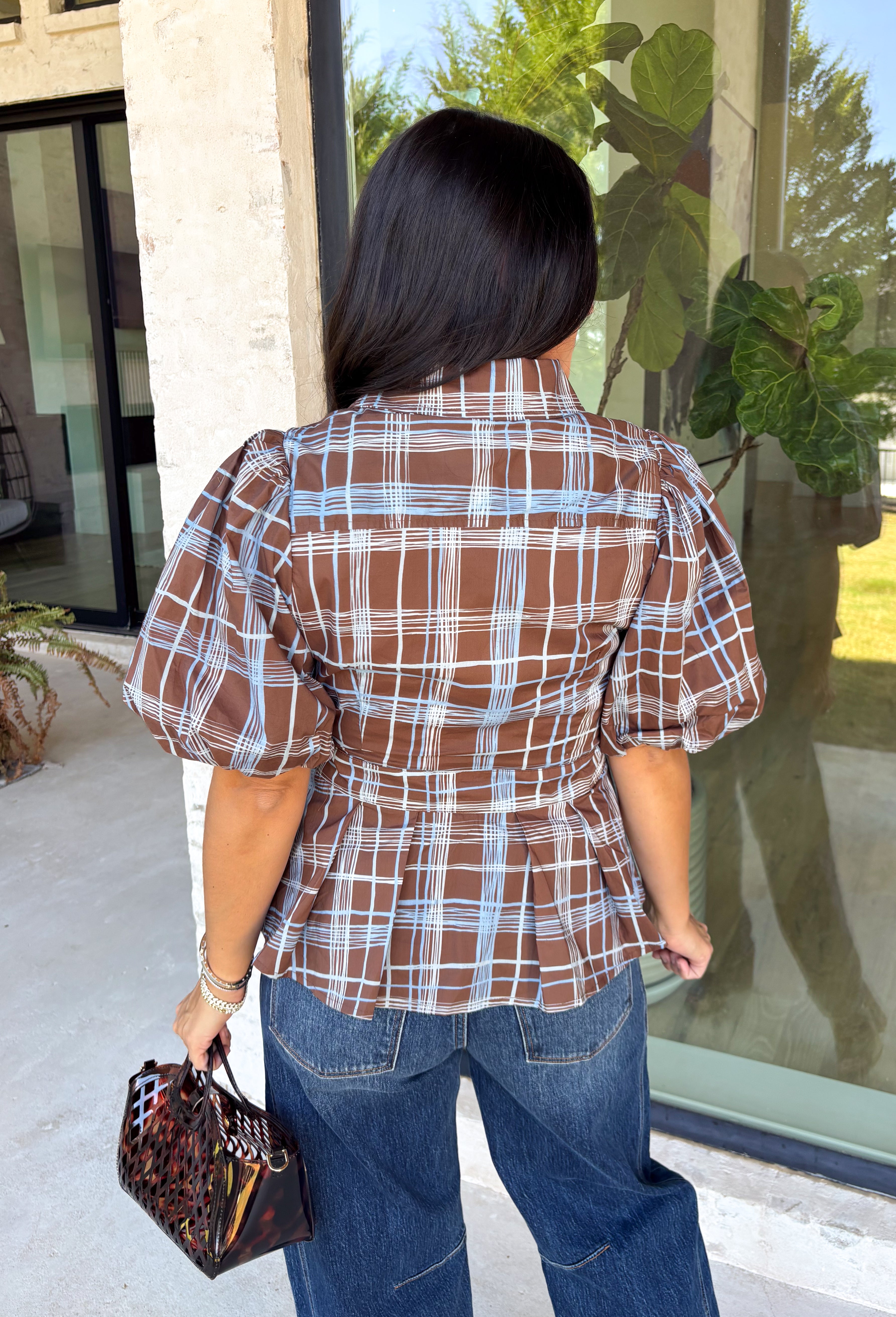 Classic plaid gets a fresh fall update with this brown and blue blouse from Entro. The mix of warm brown and cool blue creates an eye-catching color combination that fits right into your autumn wardrobe. A shirt collar and button-front closure give it a classic feel, while pleated detailing at the front and back adds shape and texture. The self-tie belt lets you define the waist, and the peplum hem creates a flattering finish that's perfect with denim or trousers. 