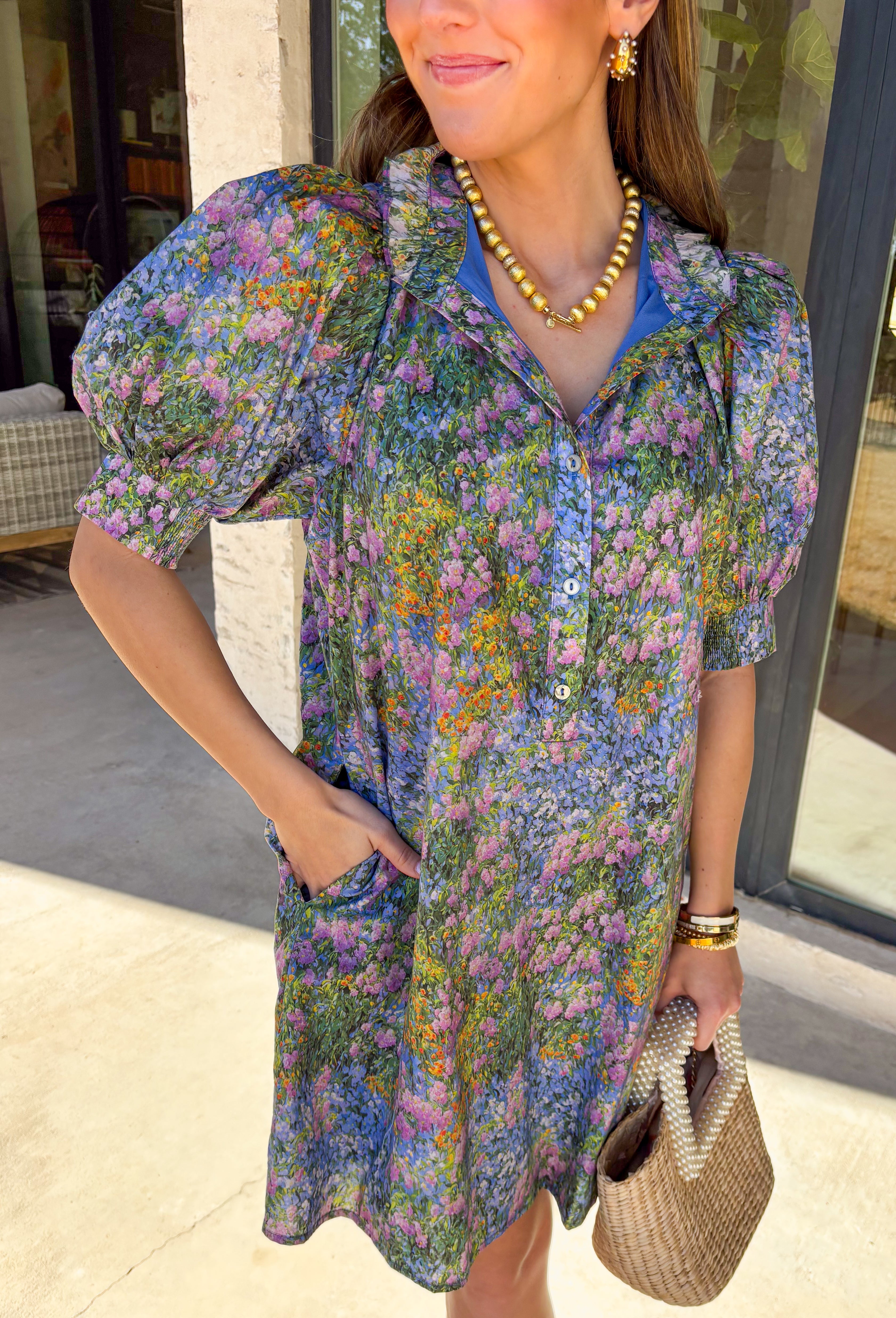 Bright, cheerful, and ready for sunny days, this blue short sleeve dress by Entro brings all the spring vibes. Featuring a colorful floral print with pops of green, purple, orange, and yellow, it’s an instant mood booster. The front button detail and subtle ruffle neckline add a sweet, polished touch, while the smocked sleeves and fully lined cotton fabric keep it comfortable and easy to wear for all day wear.