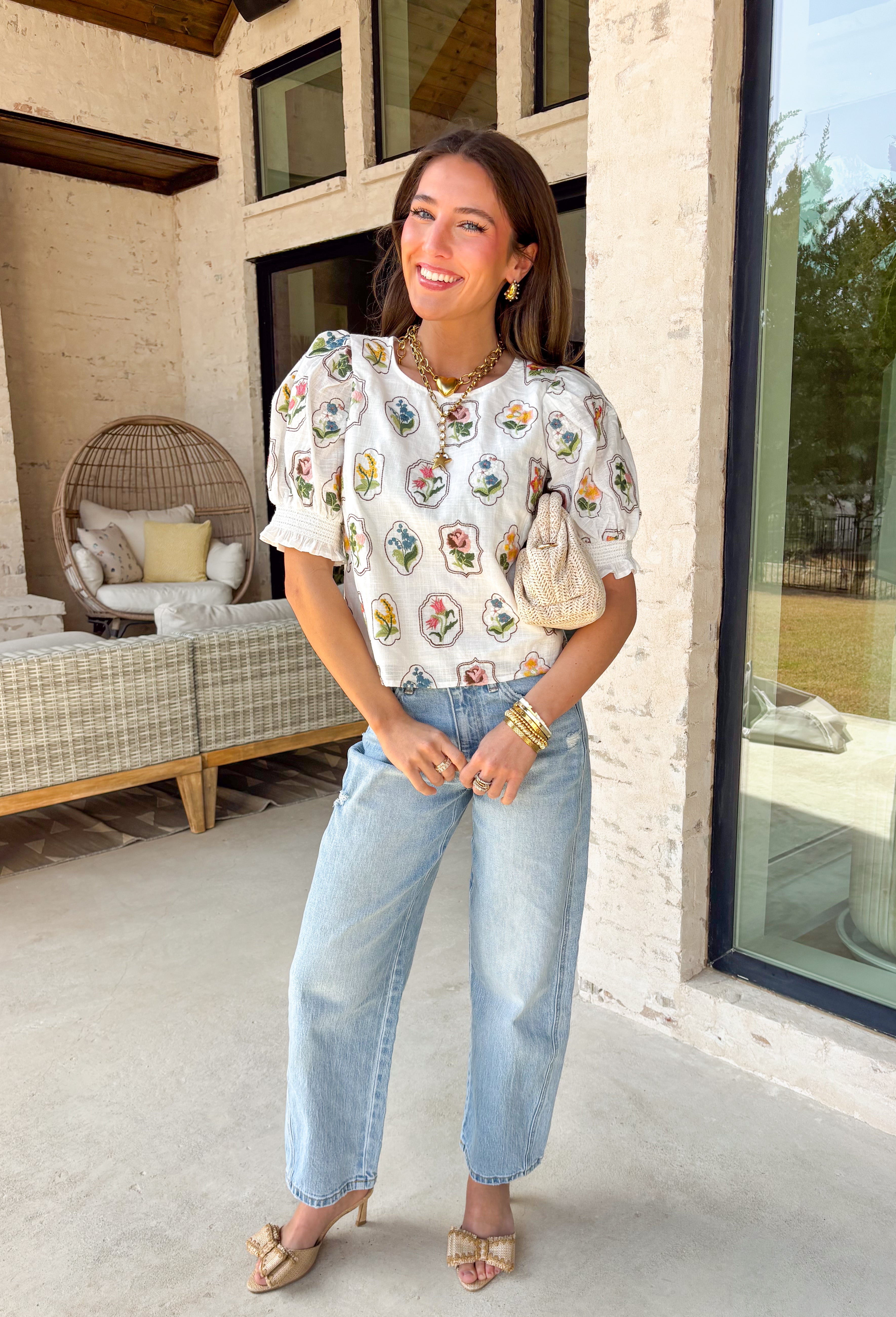 If you love a top that feels sweet, unique, and totally spring-ready, this off white top by Entro is going to be your new favorite. The patchwork-style floral embroidery along the front and sleeves is packed with beautiful color—brown, pink, green, yellow, and blue—giving it that one-of-a-kind look that instantly upgrades even your simplest denim. 