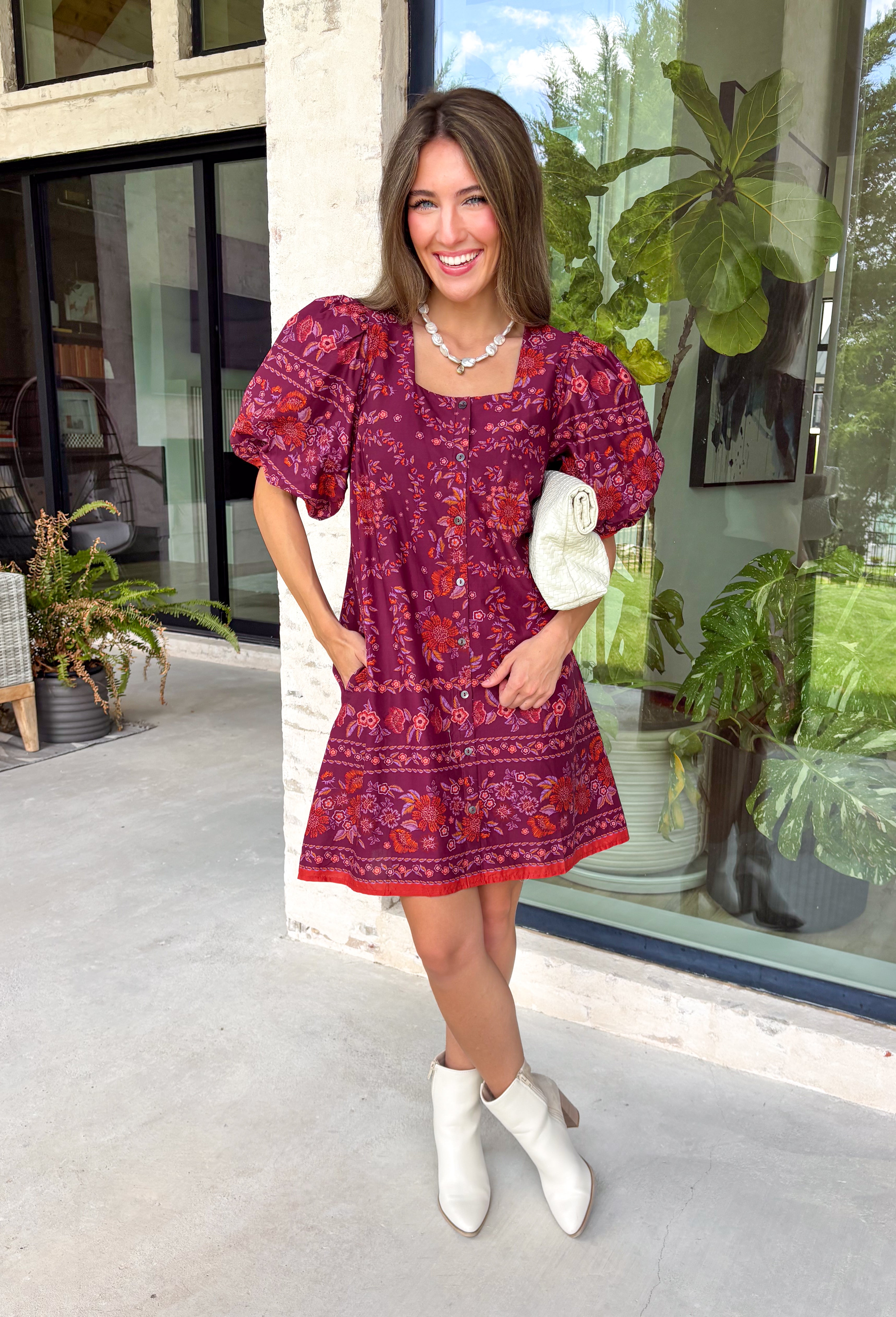 Rich fall colors and timeless details come together beautifully in this floral dress. Designed in a gorgeous burgundy hue with a vibrant orange and purple floral print, this dress captures everything we love about the season. The flattering square neckline and button-front detail create a polished, feminine silhouette, while the contrast trim adds an eye-catching finishing touch. Puff sleeves with elastic hems, side pockets, and a fully lined design make this dress as comfortable as it is charming.