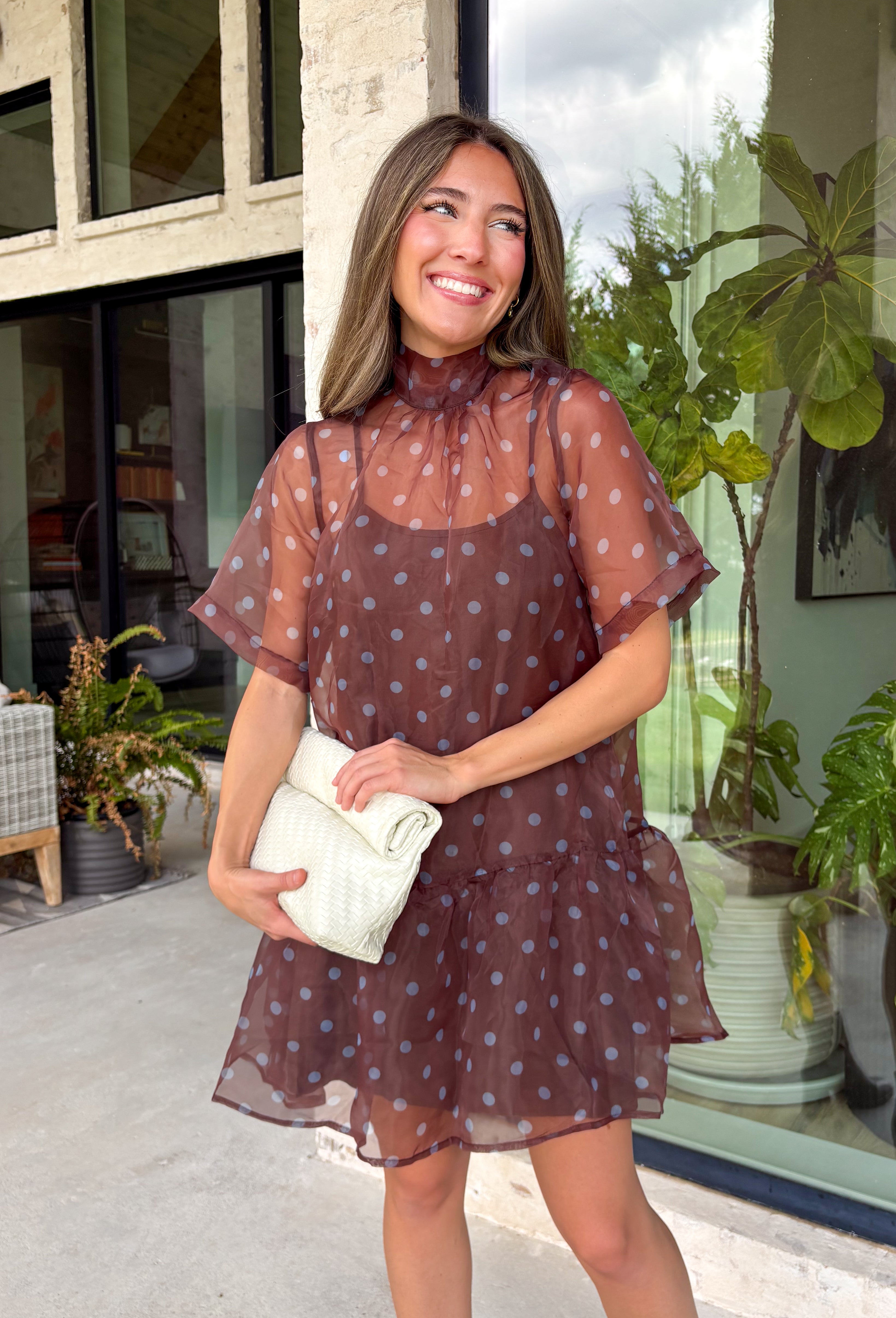 Classic polka dots get a fresh seasonal update in this charming dress from Entro. Designed with a rich brown backdrop and playful blue polka dots, this effortlessly feminine dress is perfect for everything from brunch dates to weekend outings. The high neckline creates a polished silhouette, while the back tie detail adds a sweet finishing touch. A flirty ruffle hem brings beautiful movement, and the fully lined lightweight fabric keeps you comfortable all day long.