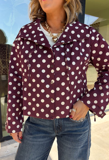 Give your fall layers a playful update with this wine-colored polka dot jacket from Entro. The rich wine shade is covered in classic white polka dots, creating a fun statement print that still pairs easily with your favorite seasonal neutrals. A collared neckline and button-down front give it a classic jacket feel, while tie details at the front and sides of the hem add a unique finishing touch. 