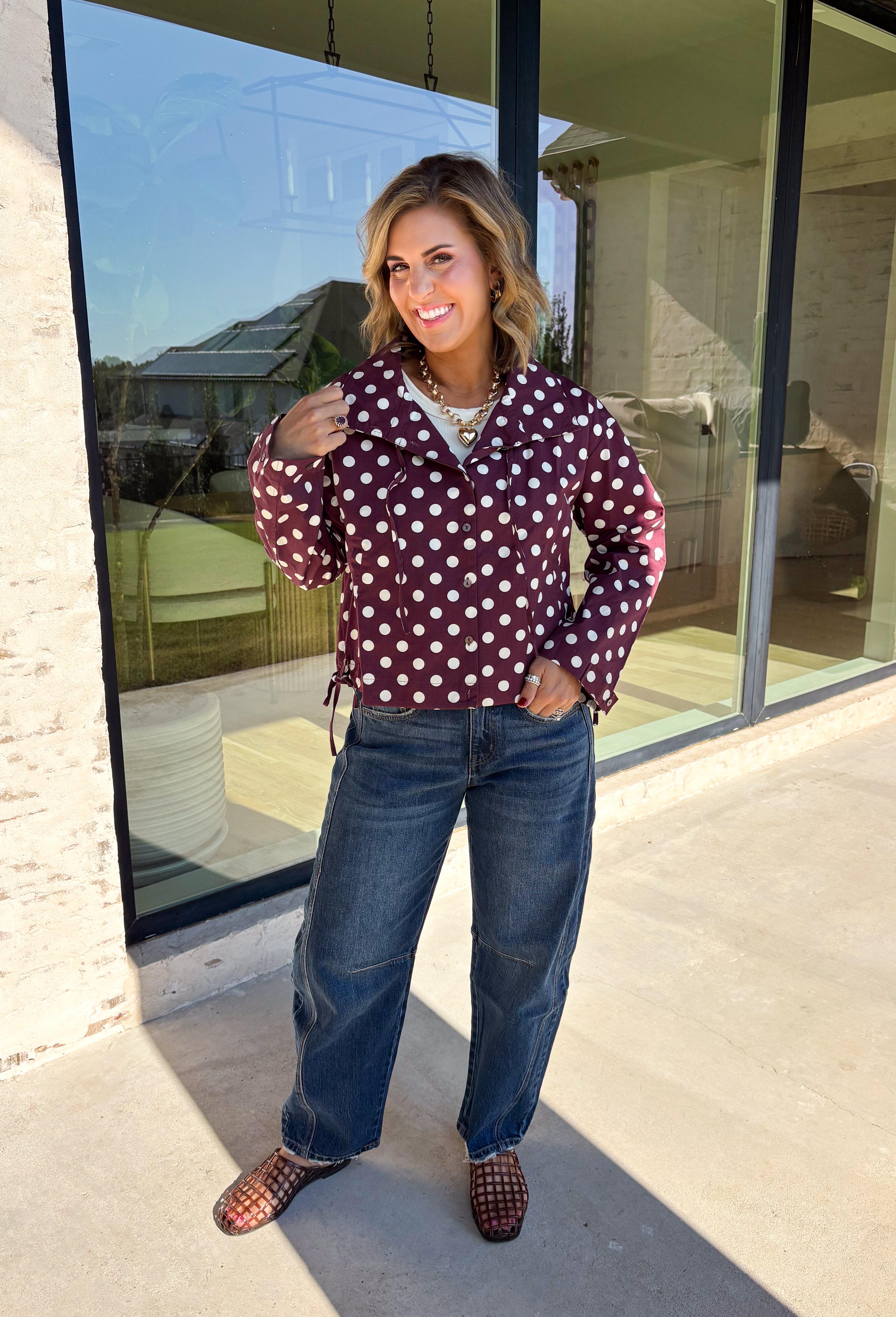 Give your fall layers a playful update with this wine-colored polka dot jacket from Entro. The rich wine shade is covered in classic white polka dots, creating a fun statement print that still pairs easily with your favorite seasonal neutrals. A collared neckline and button-down front give it a classic jacket feel, while tie details at the front and sides of the hem add a unique finishing touch. 