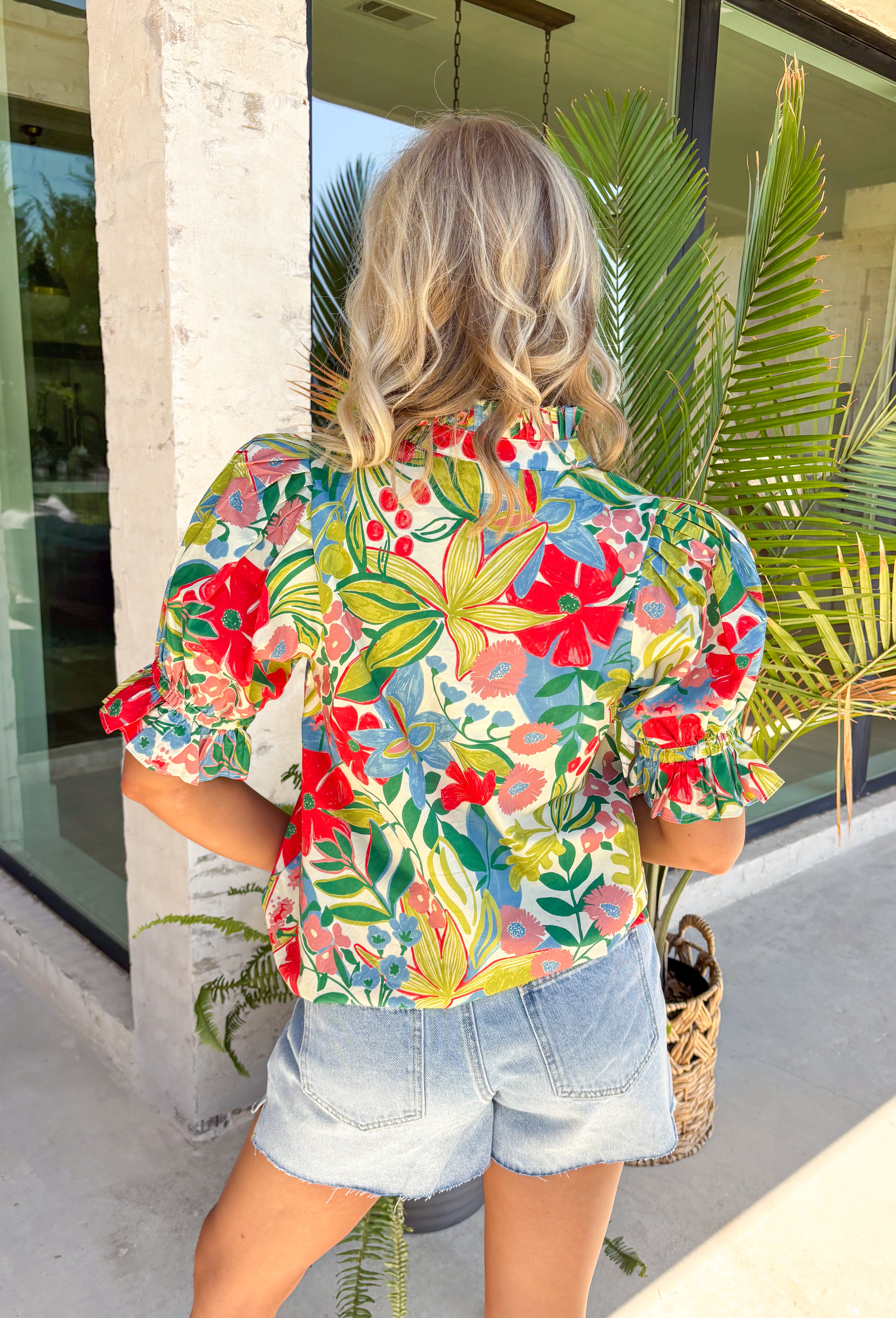 Bright, cheerful, and ready for all your spring plans, this off-white floral top by Entro is the kind of piece that instantly lifts your whole outfit. The colorful print features pops of green, red, pink, and blue for the prettiest burst of seasonal color, while the ruffled mock neck and v-neckline add a flattering, feminine touch. Finished with puff sleeves and elasticated cuffs, it’s easy to wear, easy to love, and perfect for everything from brunch to the office.