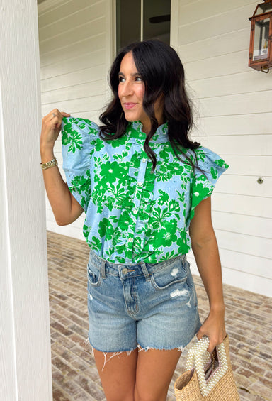 Soft, fresh, and full of spring charm! This light blue short sleeve top features a beautiful green floral print layered over textured floral eyelet lace for the prettiest dimension. It’s feminine without feeling fussy — just the right balance of sweet and polished. Designed with a classic button down front, this top is finished with a ruffle neckline and ruffle sleeves that add movement and a soft romantic touch. Crafted from breathable 100% cotton.