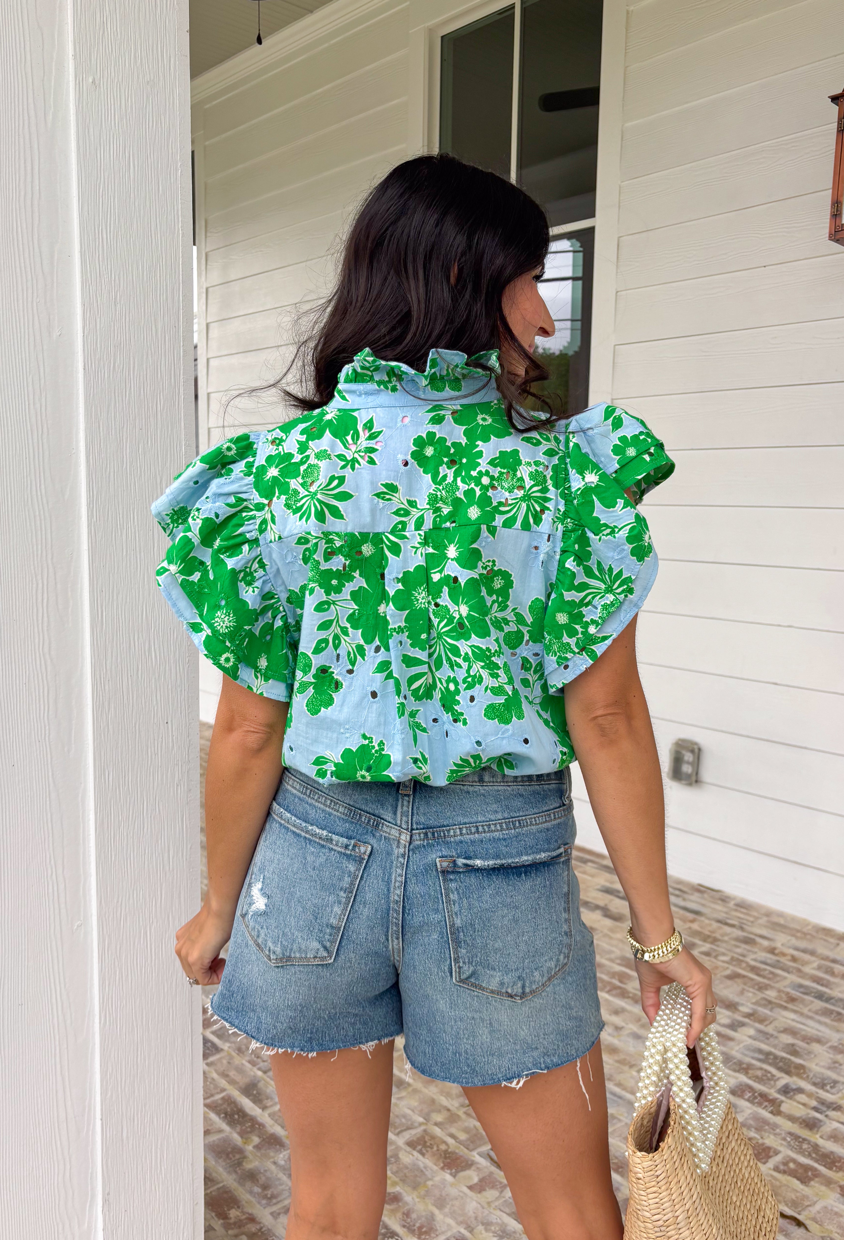 Soft, fresh, and full of spring charm! This light blue short sleeve top features a beautiful green floral print layered over textured floral eyelet lace for the prettiest dimension. It’s feminine without feeling fussy — just the right balance of sweet and polished. Designed with a classic button down front, this top is finished with a ruffle neckline and ruffle sleeves that add movement and a soft romantic touch. Crafted from breathable 100% cotton.