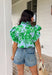 Soft, fresh, and full of spring charm! This light blue short sleeve top features a beautiful green floral print layered over textured floral eyelet lace for the prettiest dimension. It’s feminine without feeling fussy — just the right balance of sweet and polished. Designed with a classic button down front, this top is finished with a ruffle neckline and ruffle sleeves that add movement and a soft romantic touch. Crafted from breathable 100% cotton.