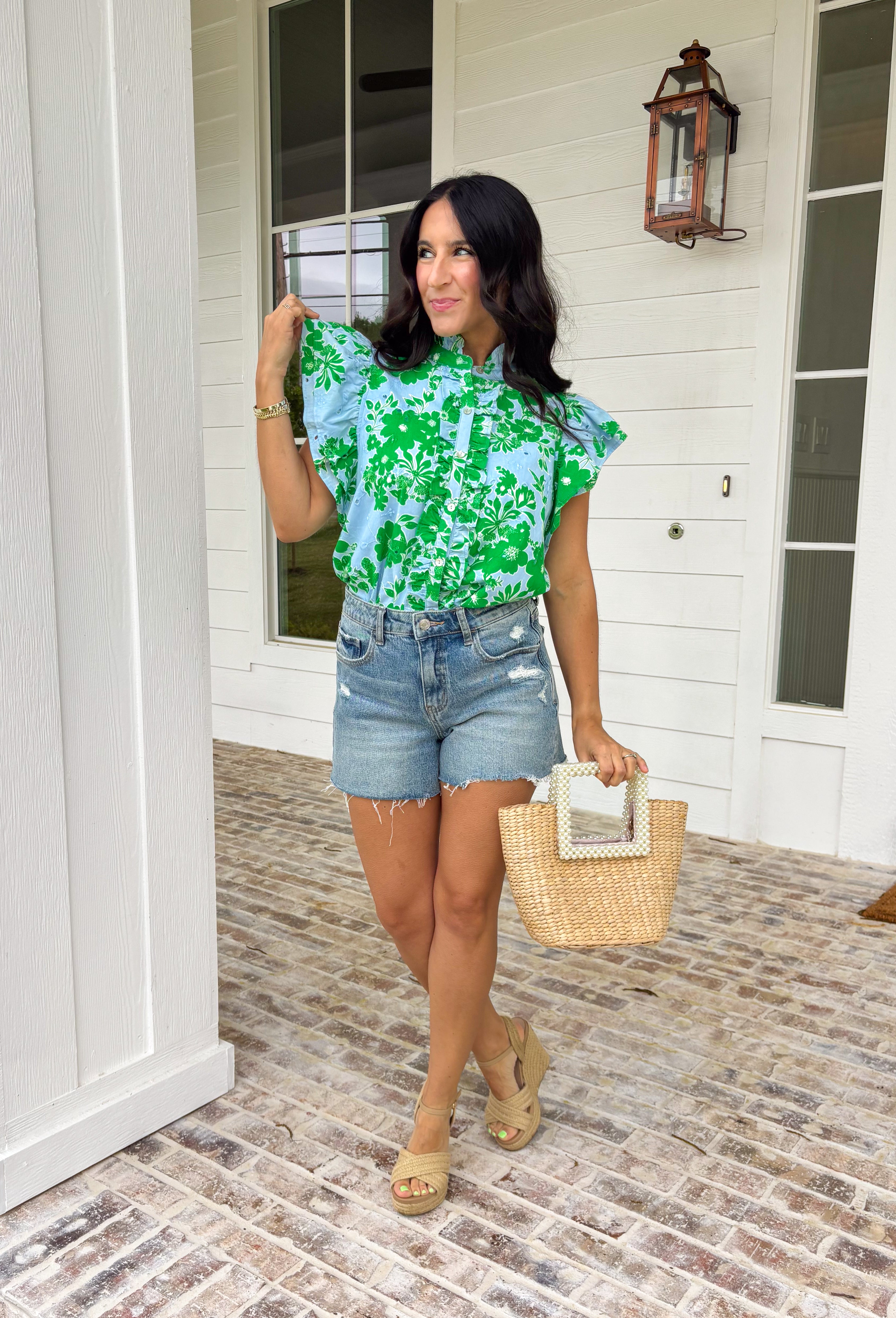 Soft, fresh, and full of spring charm! This light blue short sleeve top features a beautiful green floral print layered over textured floral eyelet lace for the prettiest dimension. It’s feminine without feeling fussy — just the right balance of sweet and polished. Designed with a classic button down front, this top is finished with a ruffle neckline and ruffle sleeves that add movement and a soft romantic touch. Crafted from breathable 100% cotton.