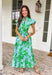 Soft, feminine, and full of spring charm! This light blue midi dress features delicate eyelet lace detailing throughout paired with a fresh green floral print for the prettiest layered texture. The subtle ruffle neckline adds a romantic touch, while the gold button details down the front bring a hint of shine. Designed with a matching self-tie closure to gently define the waist and a flowy tiered skirt for beautiful movement, this dress feels both polished and easy to wear. 