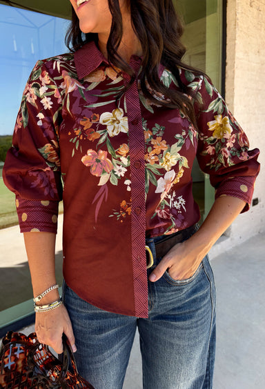 Bring a little fall color into your workweek with this burgundy floral blouse from Current Air. The rich burgundy background is covered in a seasonal floral print, while contrasting stripe trim throughout gives the design a fresh, eye-catching finish. A collared neckline and button-down front keep the look classic and work-ready, with ¾ length sleeves making it an easy choice for transitioning into cooler days. 