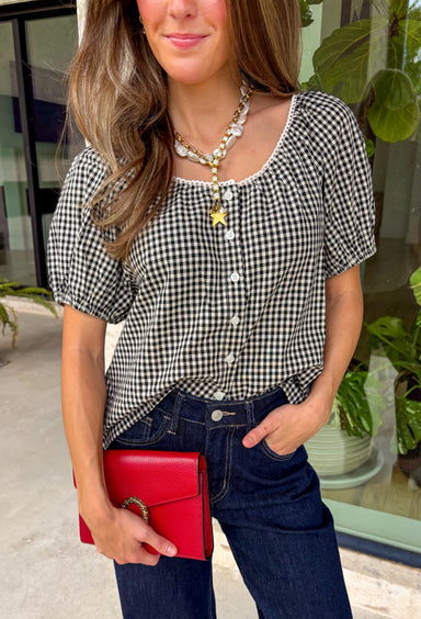 A timeless gingham print gets a feminine update in this charming button-down blouse from Twentifourth. Featuring a classic black and white gingham pattern, this versatile top is accented with delicate white scallop trim across the front for an extra touch of sweetness. The short sleeves are finished with comfortable elastic cuffs that create a soft puff silhouette, while the button-front design and breathable cotton blend make it an easy favorite for everyday wear. 