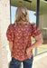 Add a touch of feminine charm to your everyday wardrobe with this beautifully detailed top from Entro. Featuring a rich brown backdrop with a pink floral print, this timeless blouse is full of thoughtful details you'll love. The ruffled neckline creates an effortlessly polished look, while the brown gingham contrast trim adds the perfect pop of classic charm. 