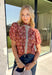 Add a touch of feminine charm to your everyday wardrobe with this beautifully detailed top from Entro. Featuring a rich brown backdrop with a pink floral print, this timeless blouse is full of thoughtful details you'll love. The ruffled neckline creates an effortlessly polished look, while the brown gingham contrast trim adds the perfect pop of classic charm. 