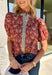 Add a touch of feminine charm to your everyday wardrobe with this beautifully detailed top from Entro. Featuring a rich brown backdrop with a pink floral print, this timeless blouse is full of thoughtful details you'll love. The ruffled neckline creates an effortlessly polished look, while the brown gingham contrast trim adds the perfect pop of classic charm. 